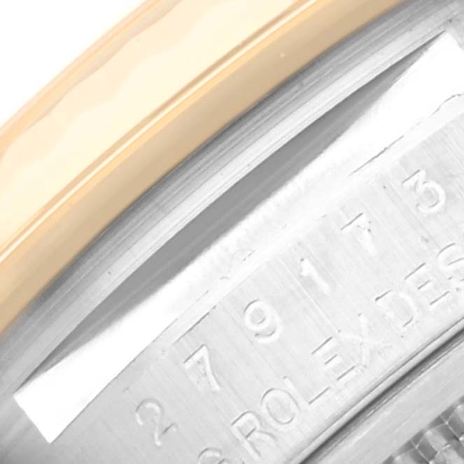 The image shows a close-up of the Datejust model by Rolex, highlighting the engraved serial number, bezel, and part of the case.