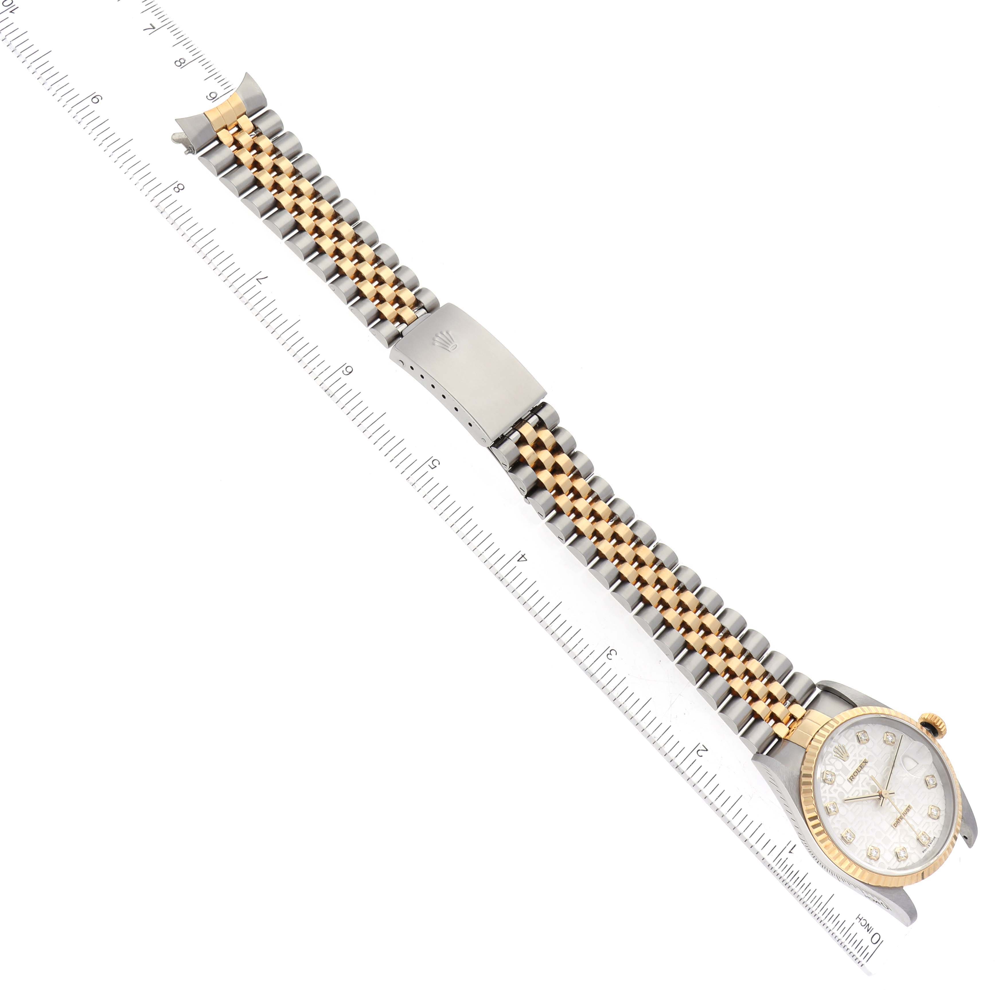 This image shows the Rolex Datejust 16233 Men's Steel and Gold (two tone) Silver Dial 16233 Men's Steel and Gold (two tone) Silver Dial watch laid flat, with a clear view of its face, band, and clasp, alongside a ruler for measurement.
