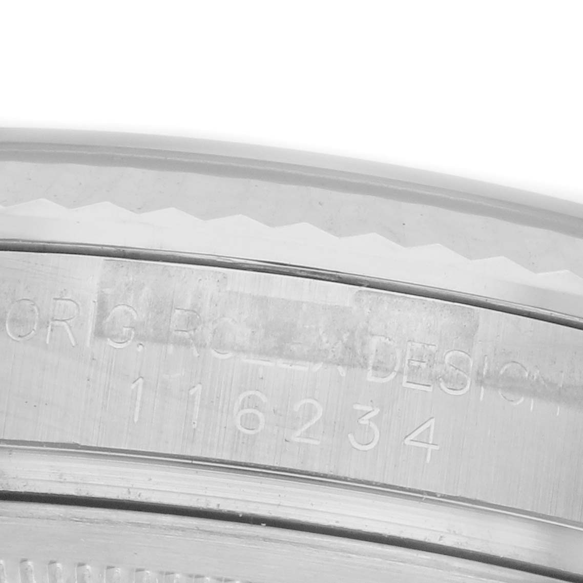 This image shows a close-up of the edge of a Rolex Datejust 116234 Men's Stainless Steel Black Dial 116234 Men's Stainless Steel Black Dial watch, highlighting engraved serial and design markings.