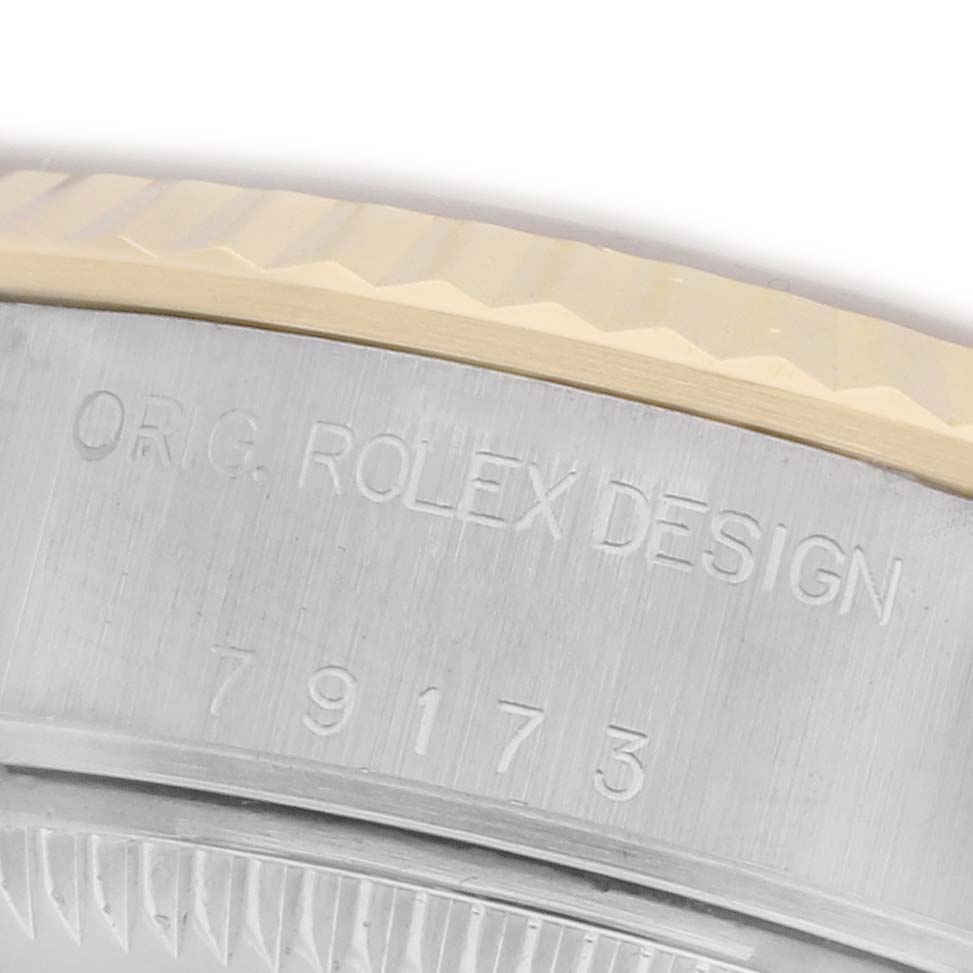 The image shows a close-up angle of the side of a Rolex Datejust 79173 Women's Steel and Gold (two tone) Champagne Dial 79173 Women's Steel and Gold (two tone) Champagne Dial, focusing on the engraved model details and bezel edge.