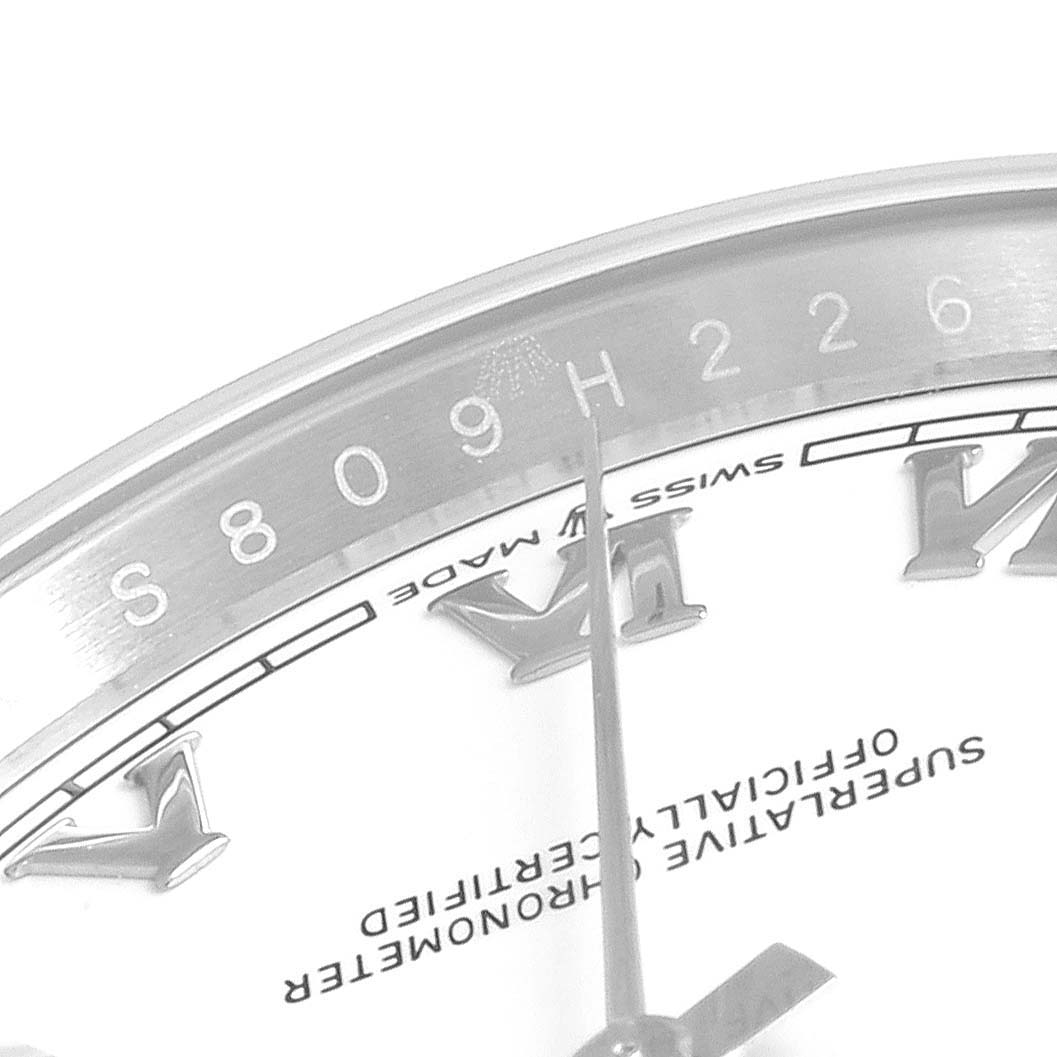 The image shows a close-up of the Rolex Datejust 126200 Men's Stainless Steel White Dial 126200 Men's Stainless Steel White Dial watch, focusing on the dial and part of the bezel with serial number detail.