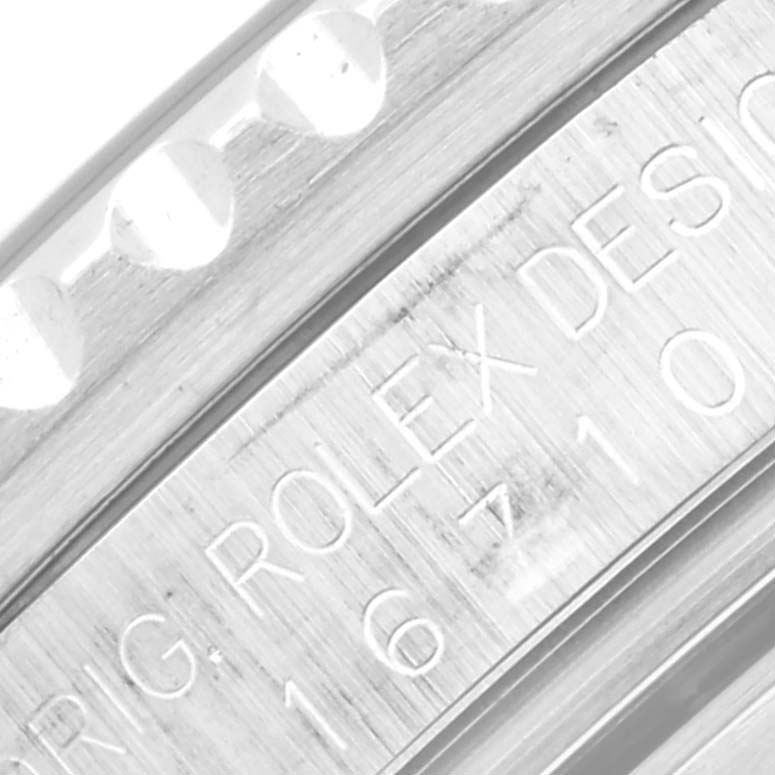 This close-up angle of a Rolex GMT-Master 16710 Men's Stainless Steel Black Dial 16710 Men's Stainless Steel Black Dial watch shows the engraved model number and part of the bezel with its detailing.