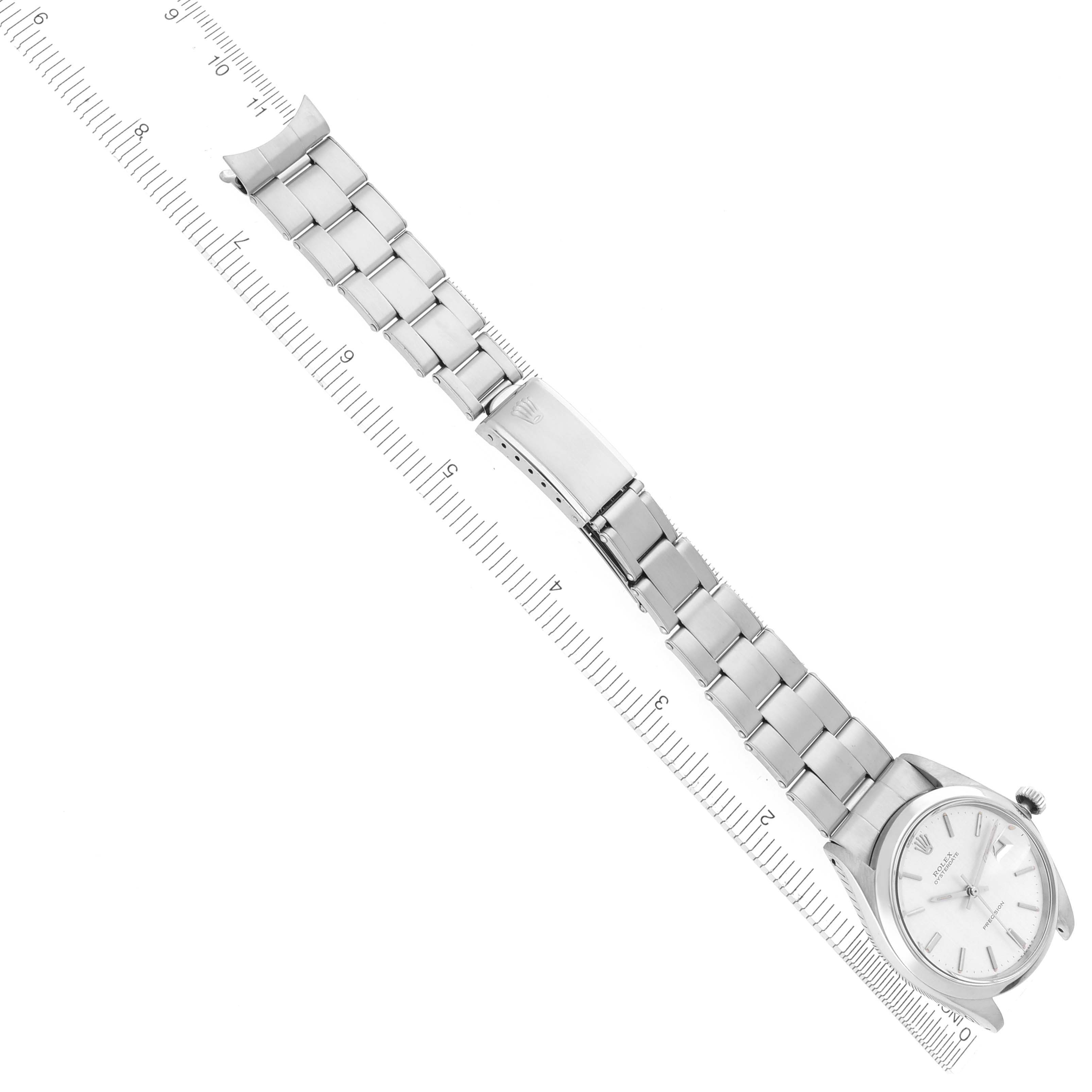 The Rolex Date 6694 Men's Stainless Steel Silver Dial 6694 Men's Stainless Steel Silver Dial watch is shown at a top-down angle, displaying the full bracelet and clasp alongside a measurement scale.