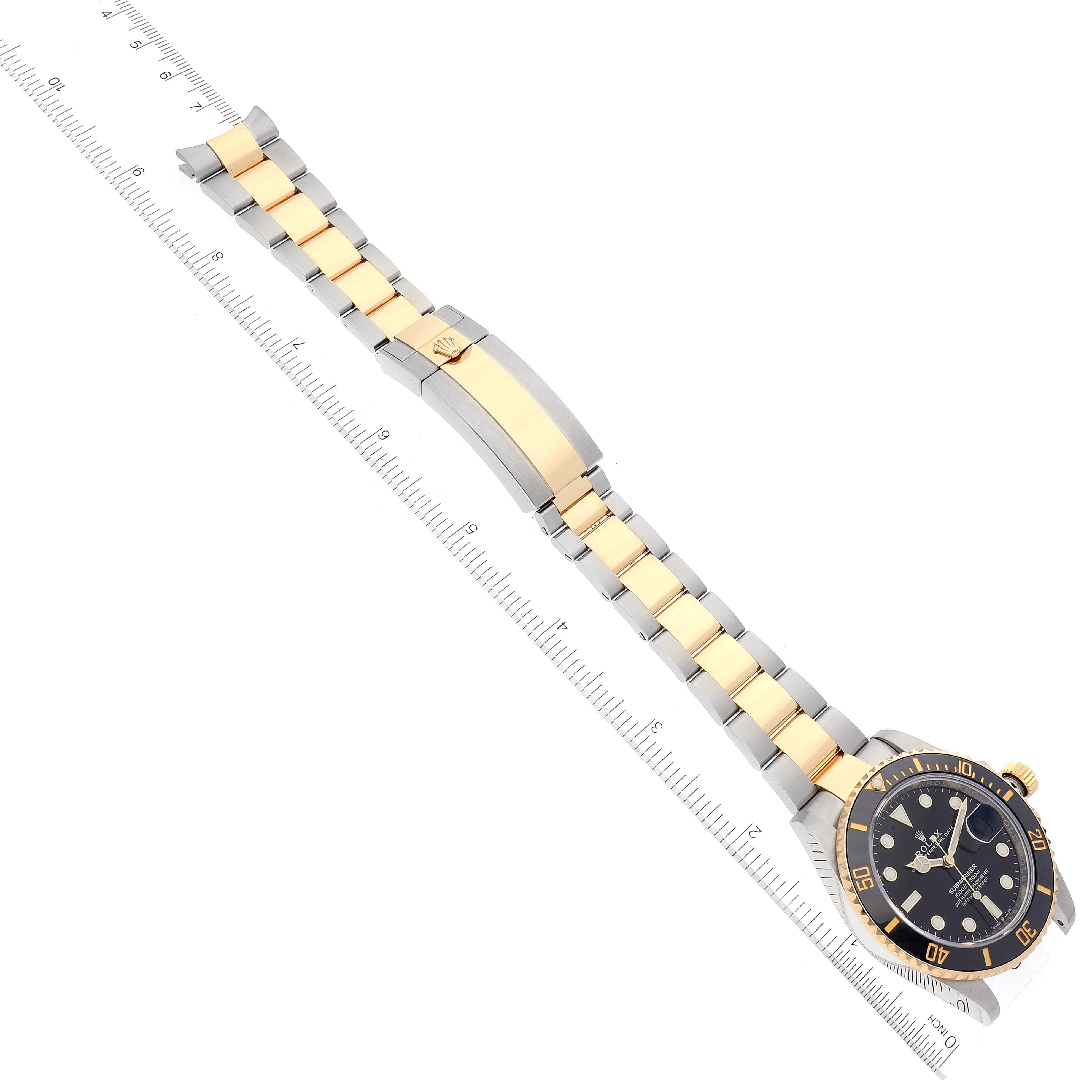 The image shows a Rolex Submariner 126613 Men's Steel and Gold (two tone) Black Dial 126613 Men's Steel and Gold (two tone) Black Dial watch with a two-tone bracelet and a ruler, viewed from the top.