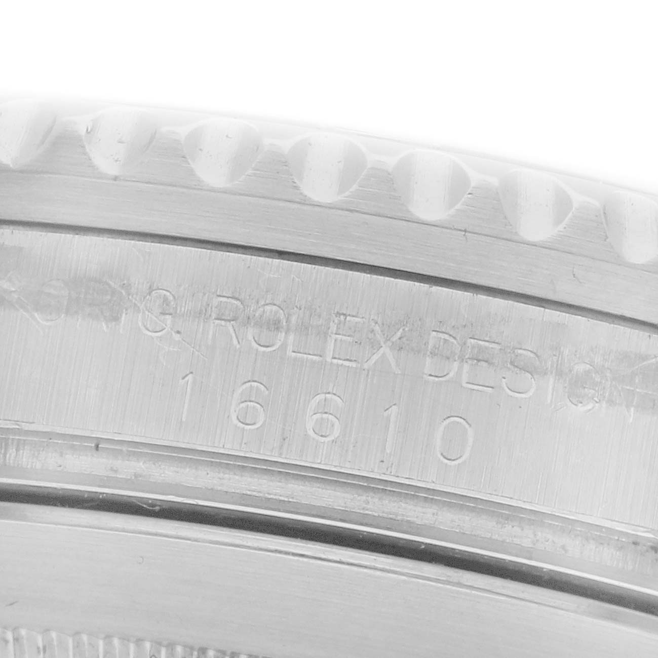 The image shows a close-up of the engraved edge of a Rolex Submariner 16610 Men's Stainless Steel Black Dial 16610 Men's Stainless Steel Black Dial, focusing on the serial and model number.