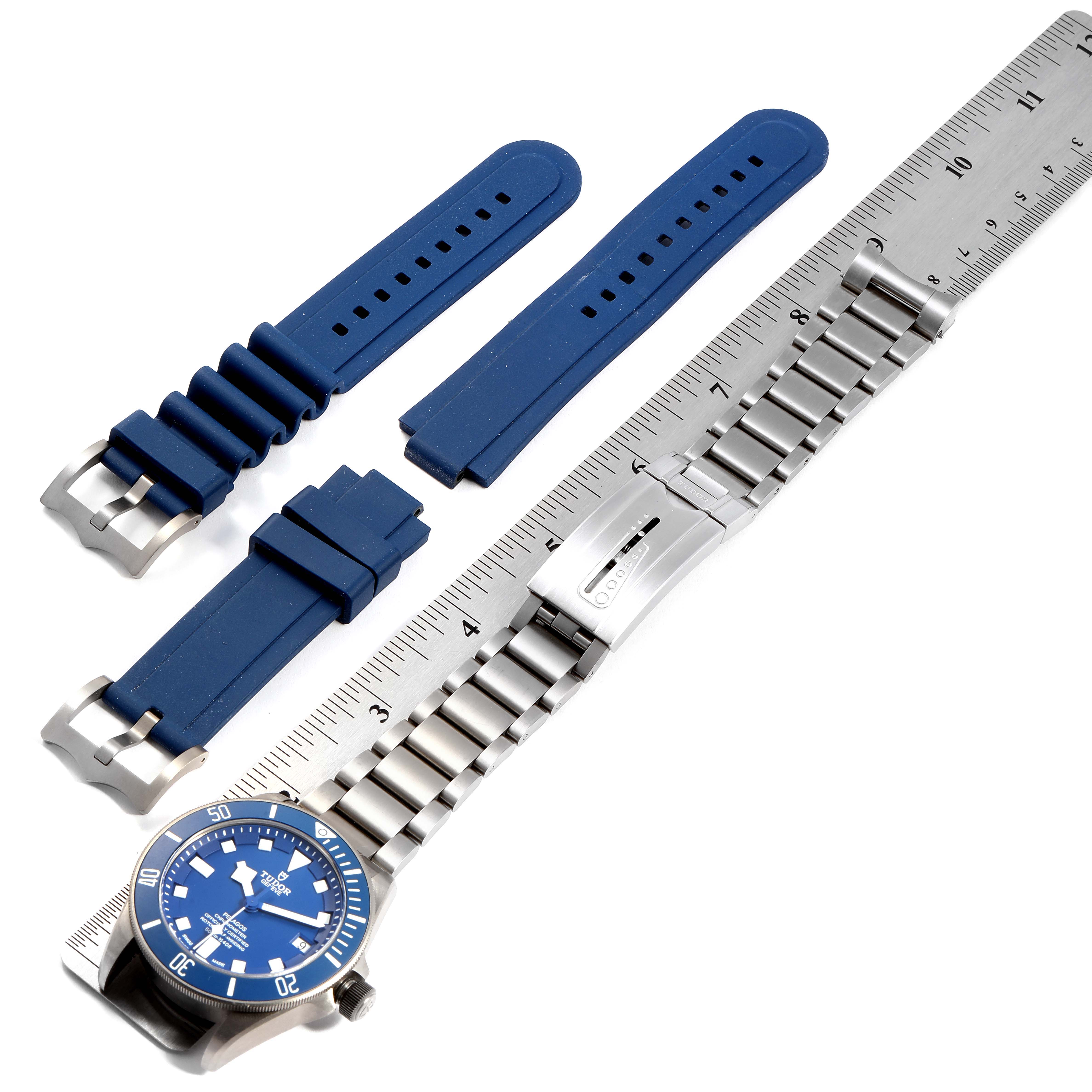 The image displays a Tudor Pelagos 25600TB Men's Titanium Blue Dial 25600TB Men's Titanium Blue Dial watch, its metal bracelet, and blue rubber straps alongside a ruler.