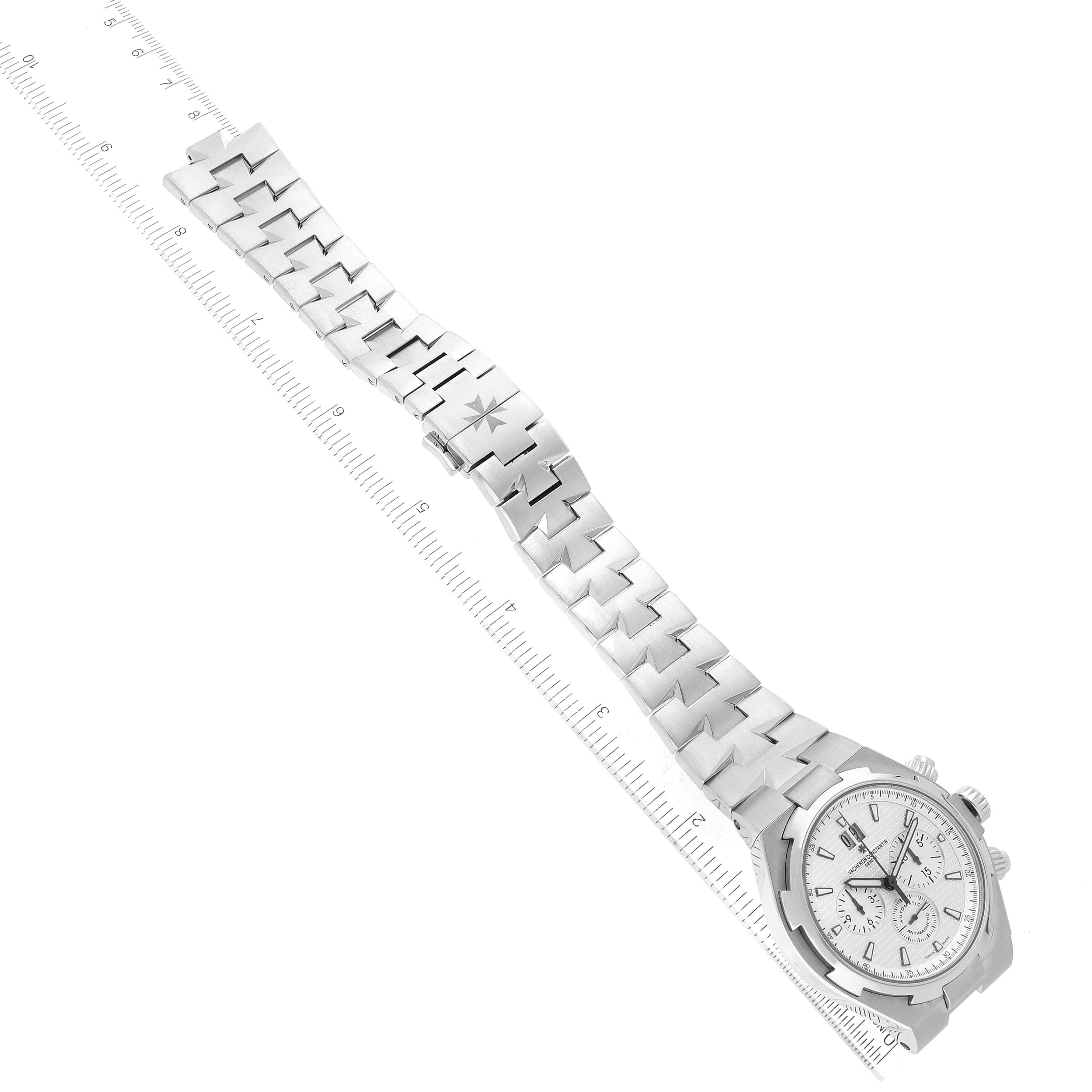 The image shows a Vacheron Constantin Overseas 49150/B01A-9095 Men's Stainless Steel Silver Dial 49150/B01A-9095 Men's Stainless Steel Silver Dial model watch laid flat with a ruler for measurement, displaying the watch face and bracelet.