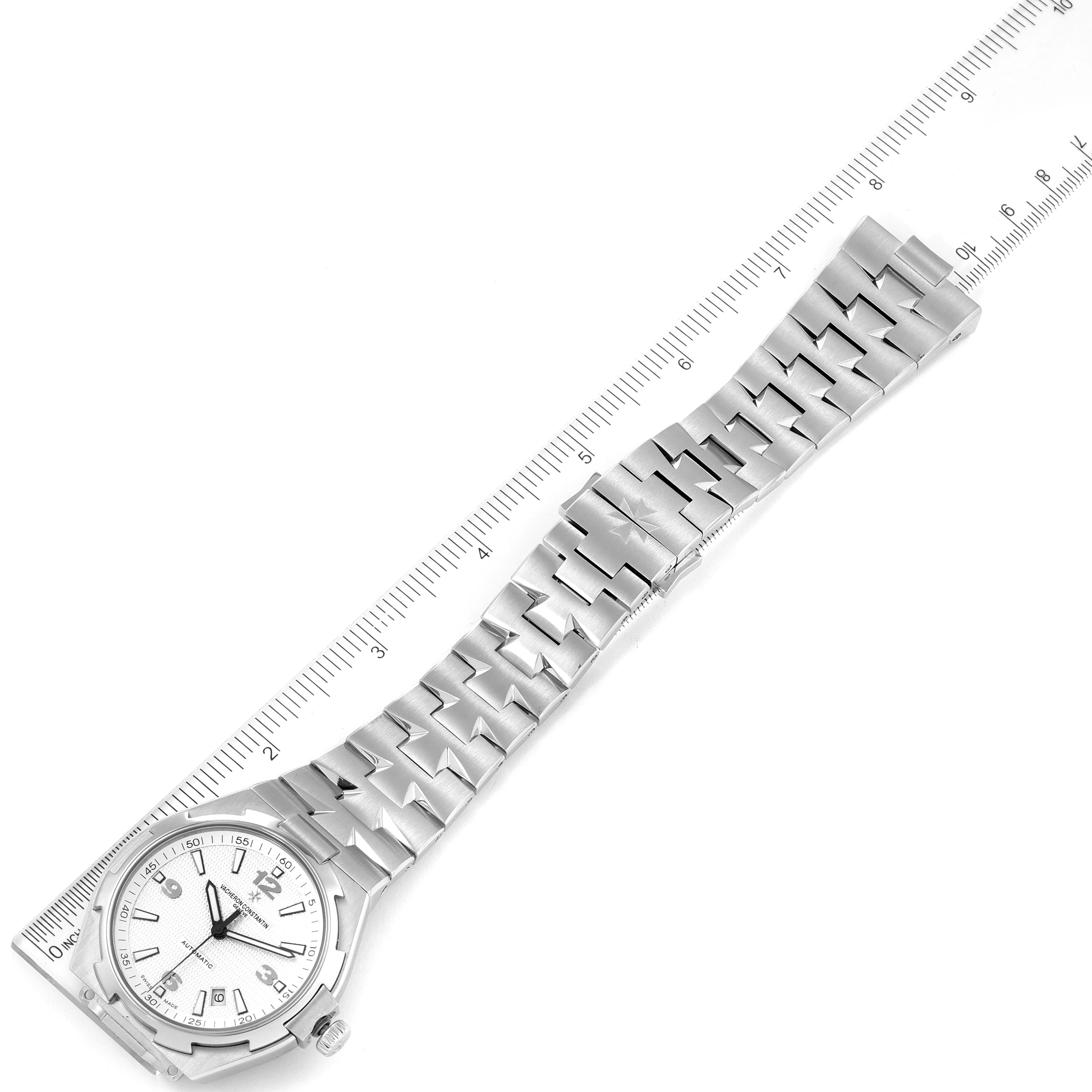 The image shows a Vacheron Constantin Overseas 47040B01A-9093 Men's Stainless Steel Silver Dial 47040B01A-9093 Men's Stainless Steel Silver Dial watch from a top view, detailing its bracelet and watch face with a ruler alongside.