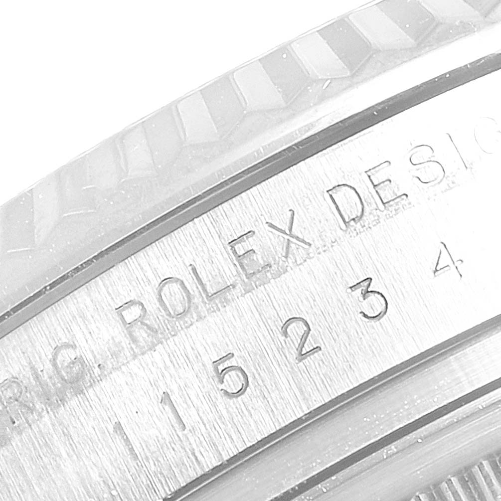 This image shows a close-up of the side of a Rolex Date 115234 Men's Stainless Steel Black Dial 115234 Men's Stainless Steel Black Dial model, featuring engraved text and partial bezel.