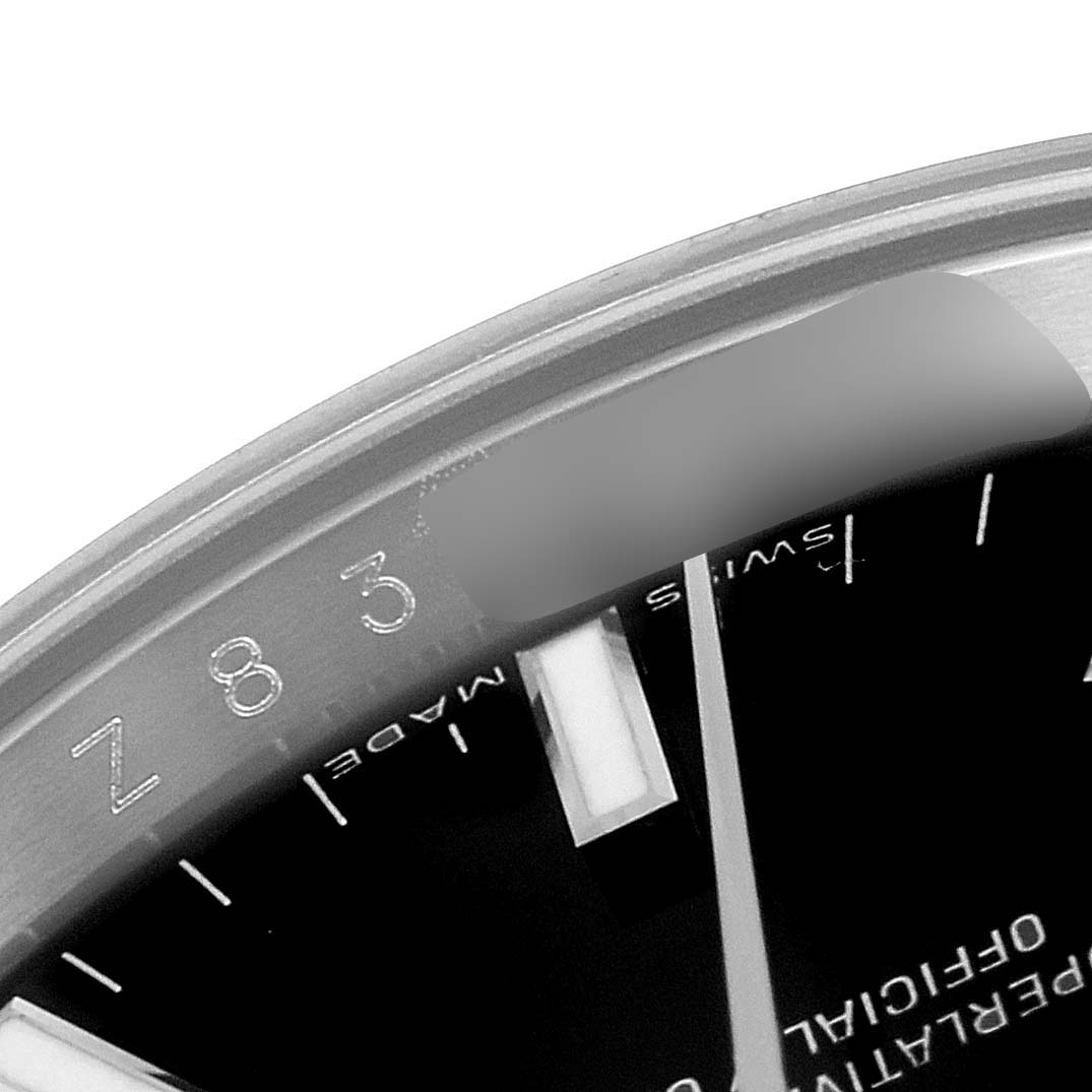 This close-up image of a Rolex Date 115234 Men's Stainless Steel Black Dial 115234 Men's Stainless Steel Black Dial model watch shows the edge of the dial and part of the bezel.