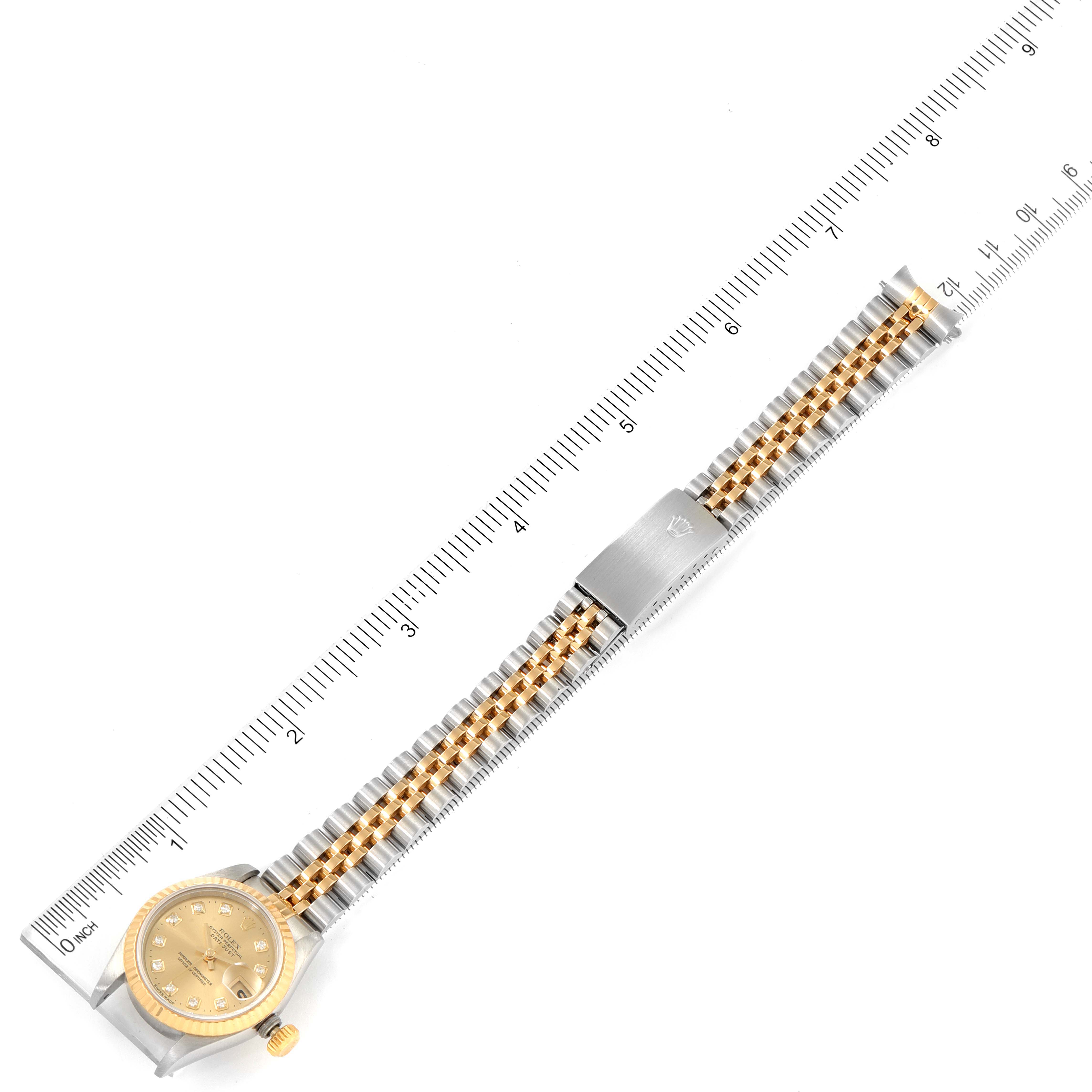 The Rolex Datejust 69173 Women
s Steel and Gold (two tone) Champagne Dial 69173 Women
s Steel and Gold (two tone) Champagne Dial watch is shown from a top-down angle, highlighting its face, crown, and full bracelet with a ruler for scale.
