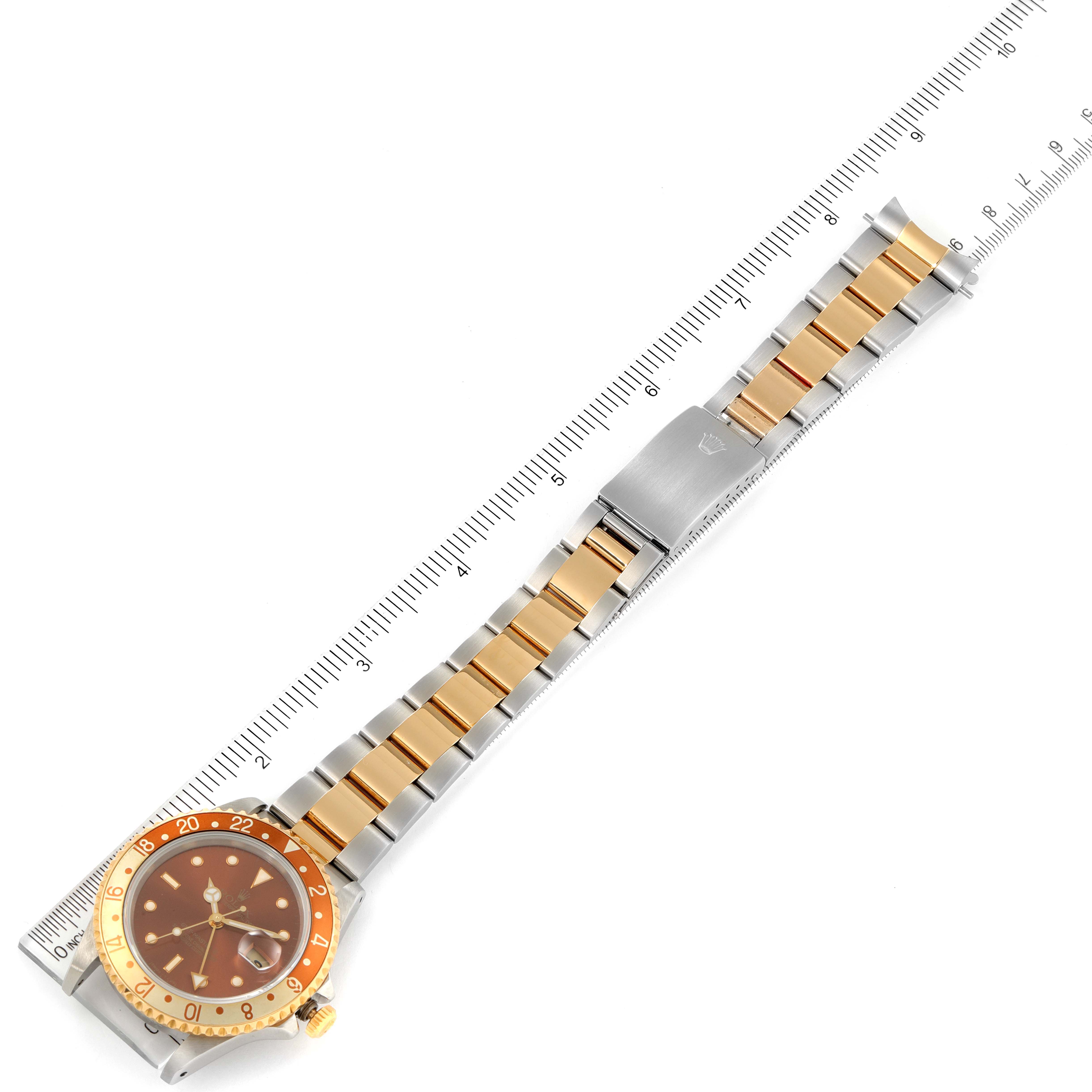 The image shows a Rolex GMT-Master 16713 Men's Steel and Gold (two tone) Brown Dial 16713 Men's Steel and Gold (two tone) Brown Dial watch displayed flat with a stainless steel and gold bracelet against a ruler for scale.