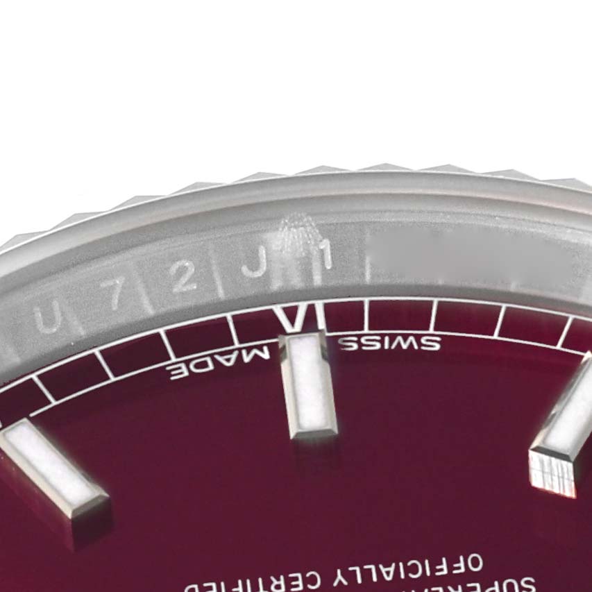 The image shows the upper portion of the dial and part of the bezel of a Rolex President 118139 Men
s White Gold Red Dial 118139 Men
s White Gold Red Dial model watch.