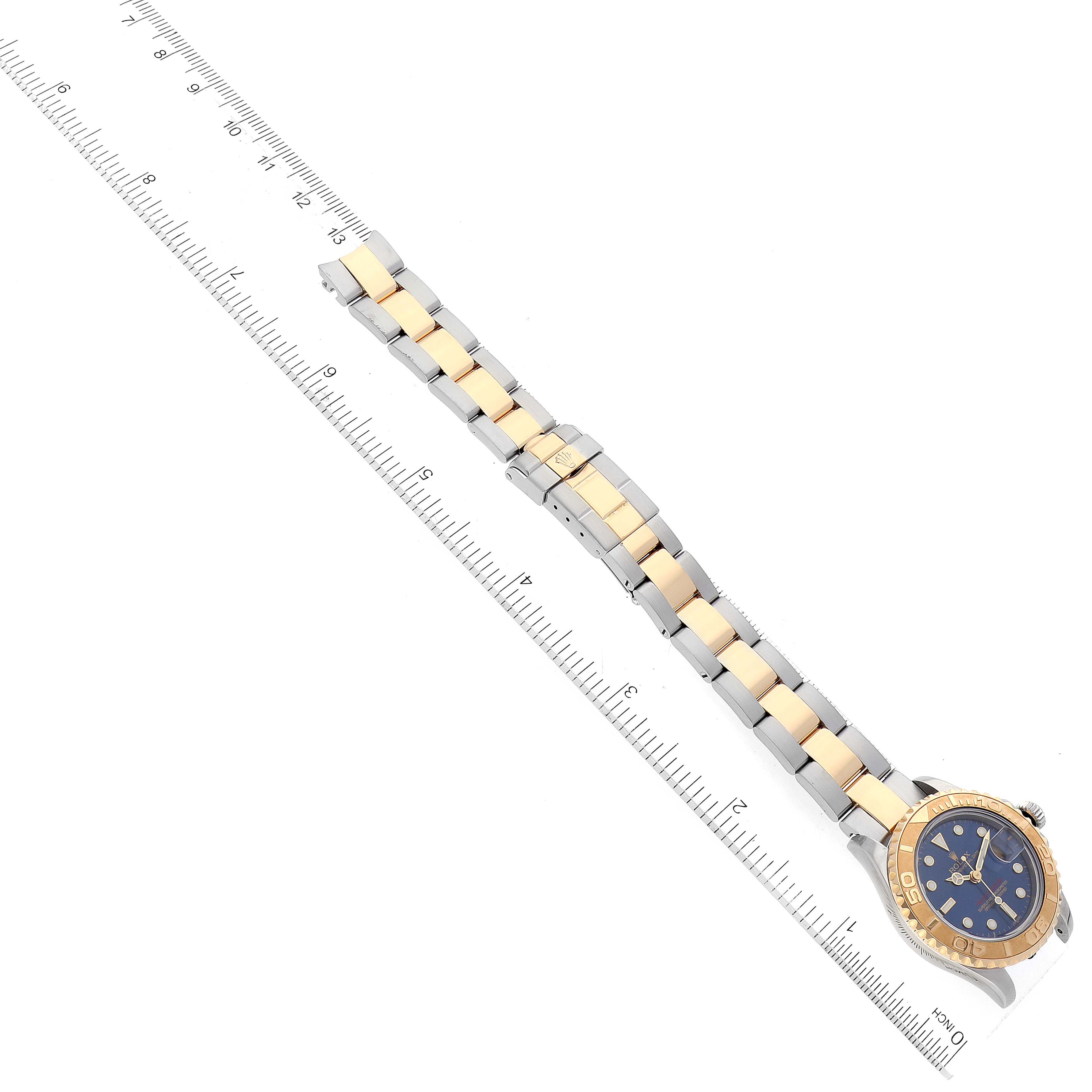 This image shows the full length of a Rolex Yacht-Master 69623 Women's Steel and Gold (two tone) Blue Dial 69623 Women's Steel and Gold (two tone) Blue Dial model watch placed next to a ruler, highlighting the strap and face.