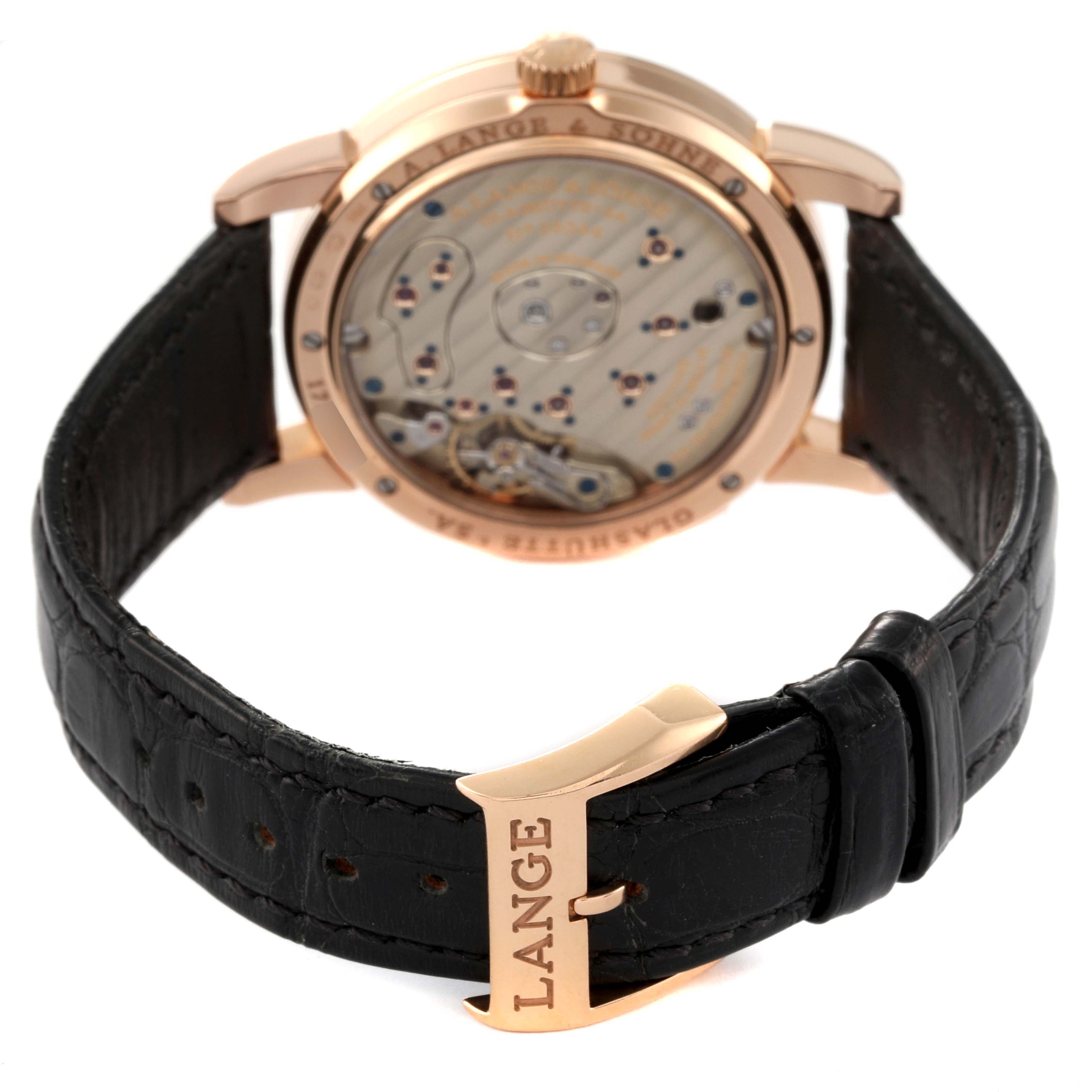 The image shows the back view of the Lange 1 model by A. Lange & Sohne, highlighting its movement and the clasp with "LANGE" branding.