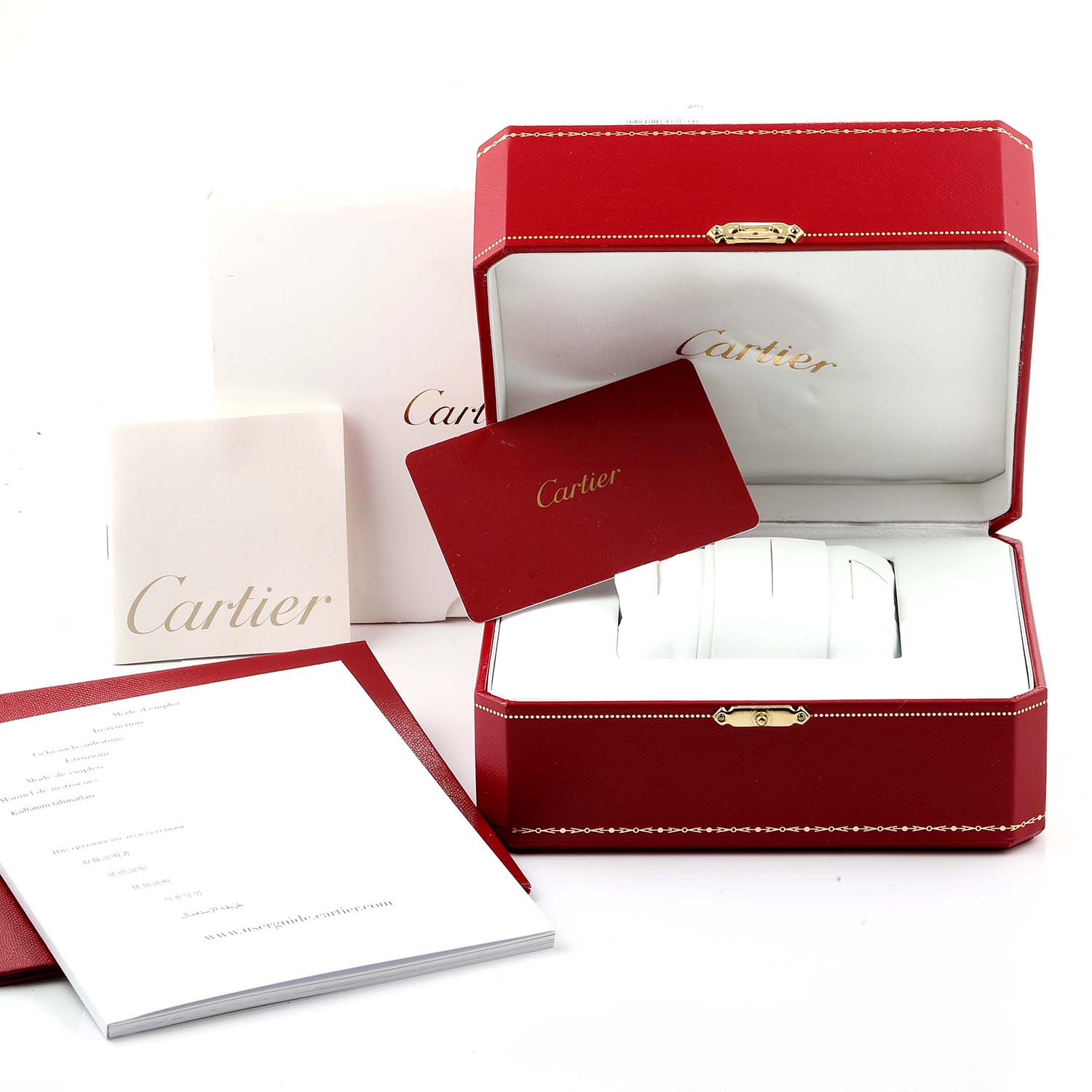 The image shows a Cle de Cartier watch box, open, with accompanying manuals and certificates in the background.