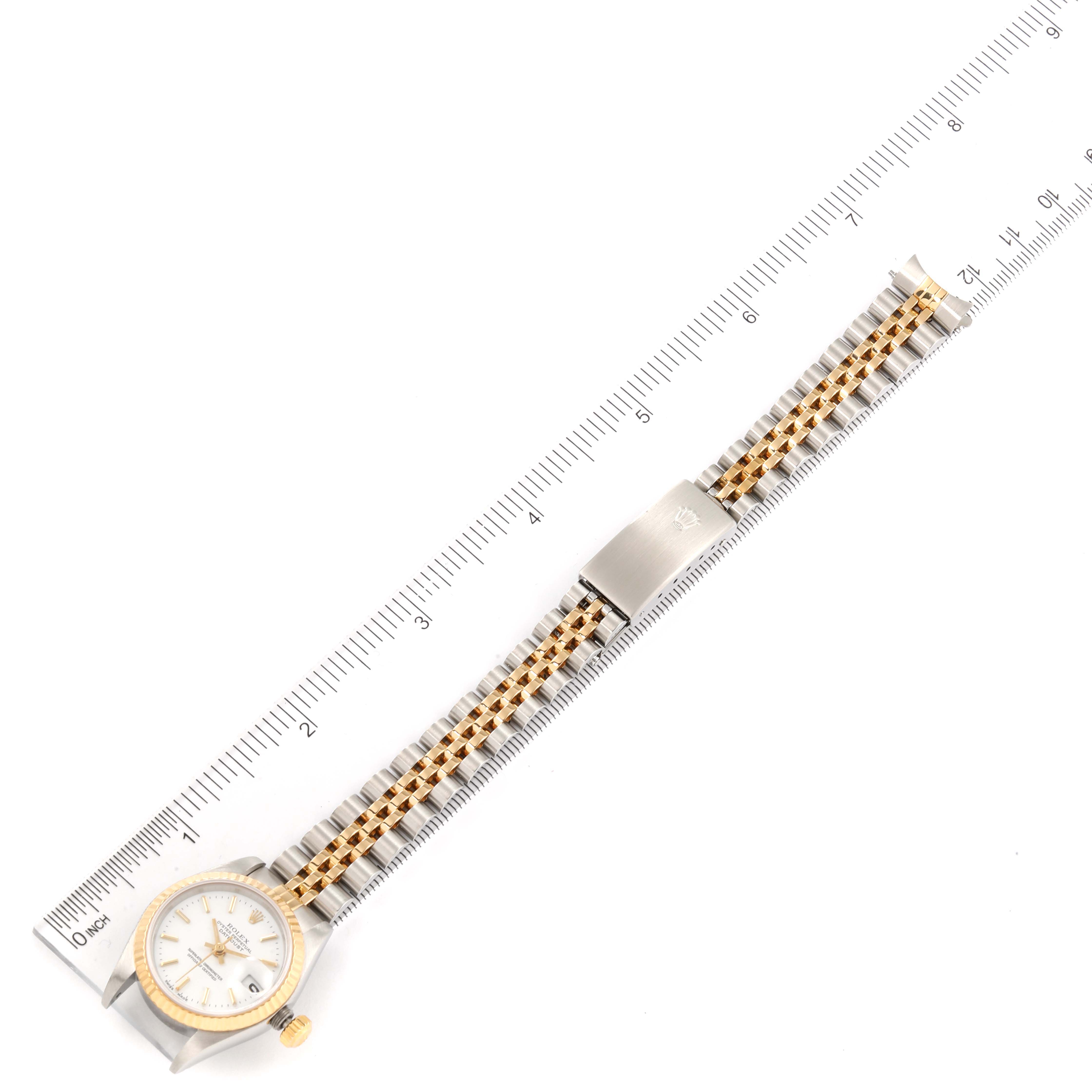 The image shows a top-down view of a Rolex Datejust 79173 Women's Steel and Gold (two tone) White Dial 79173 Women's Steel and Gold (two tone) White Dial watch with a two-tone band and a ruler for scale.