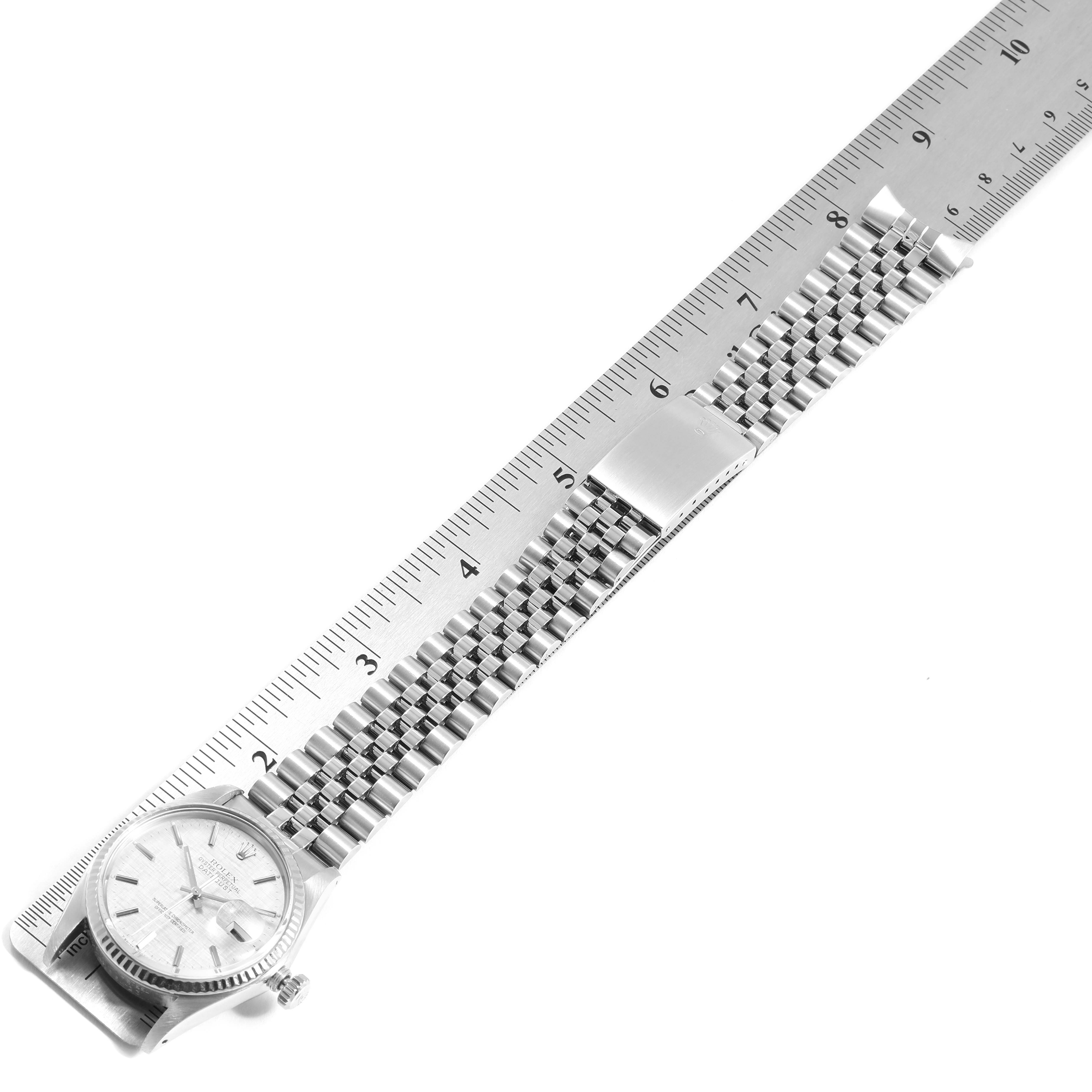 The image shows the front of a Rolex Datejust 16014 Men
s Stainless Steel Silver Dial 16014 Men
s Stainless Steel Silver Dial watch with its bracelet placed next to a ruler for measurement.