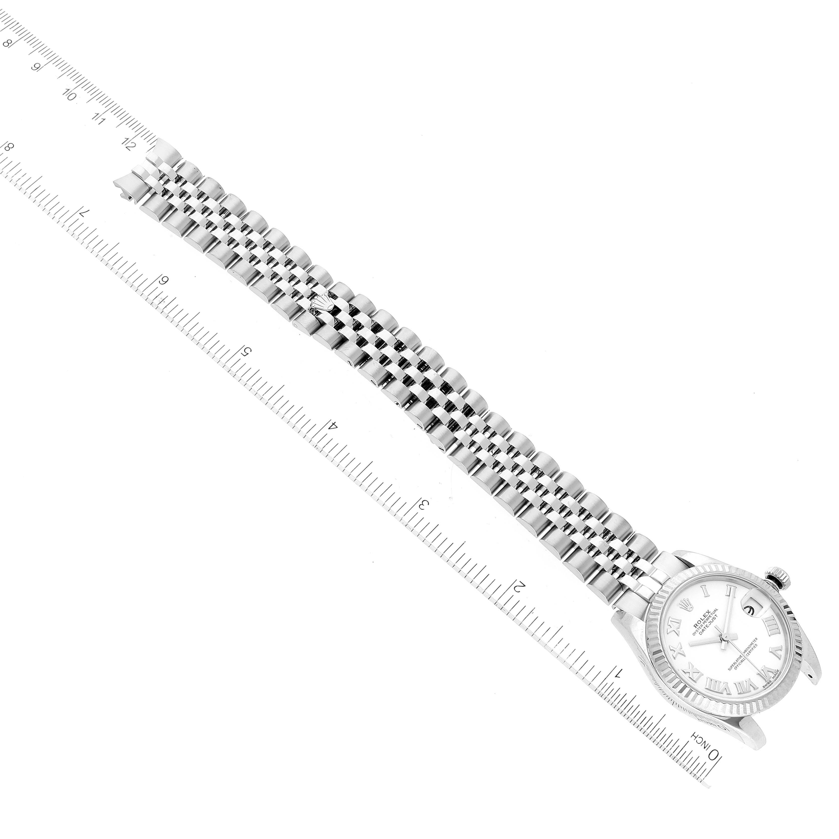 This image displays a Rolex Mid-Size 178274 Women
s Stainless Steel White Dial 178274 Women
s Stainless Steel White Dial watch laid flat with a visible face, the full bracelet, and an adjacent ruler for scale.