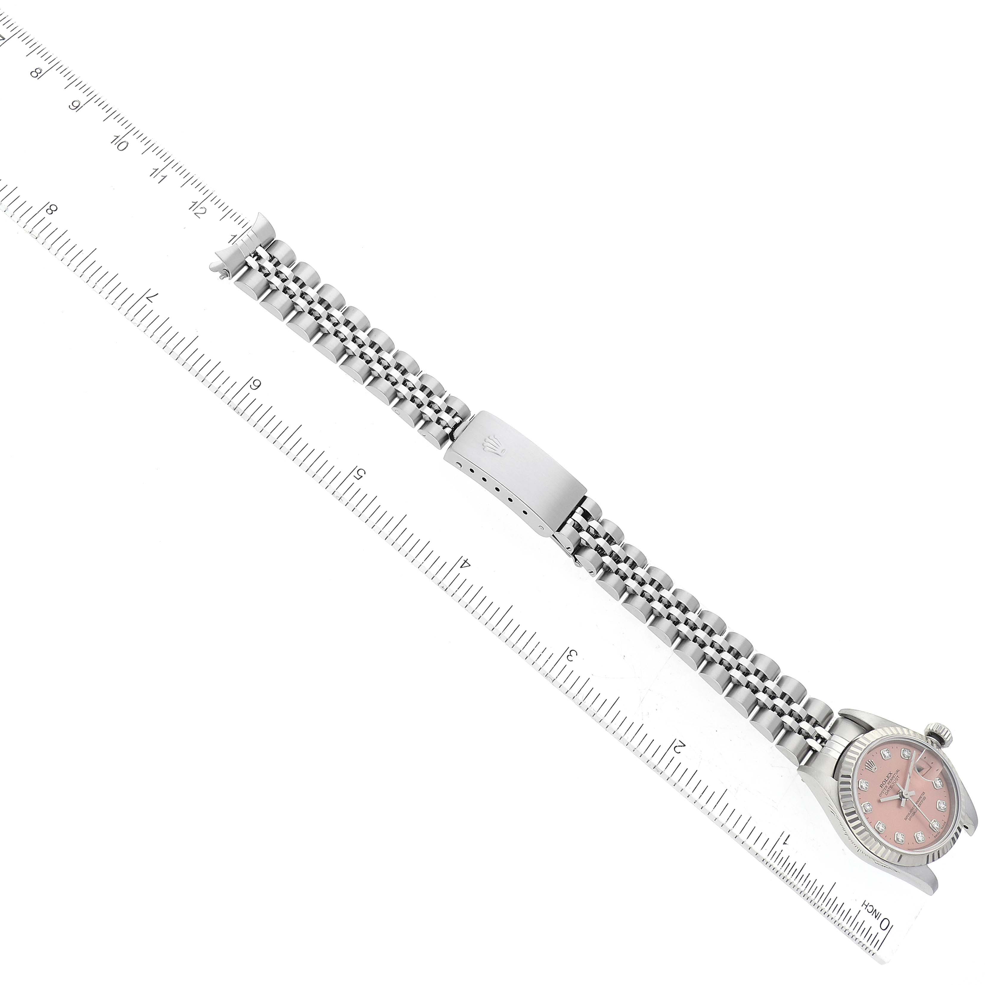 The Rolex Datejust 69174 Women's Stainless Steel Pink Dial 69174 Women's Stainless Steel Pink Dial watch is shown from above, displaying the face, bracelet, and clasp next to a ruler for size reference.