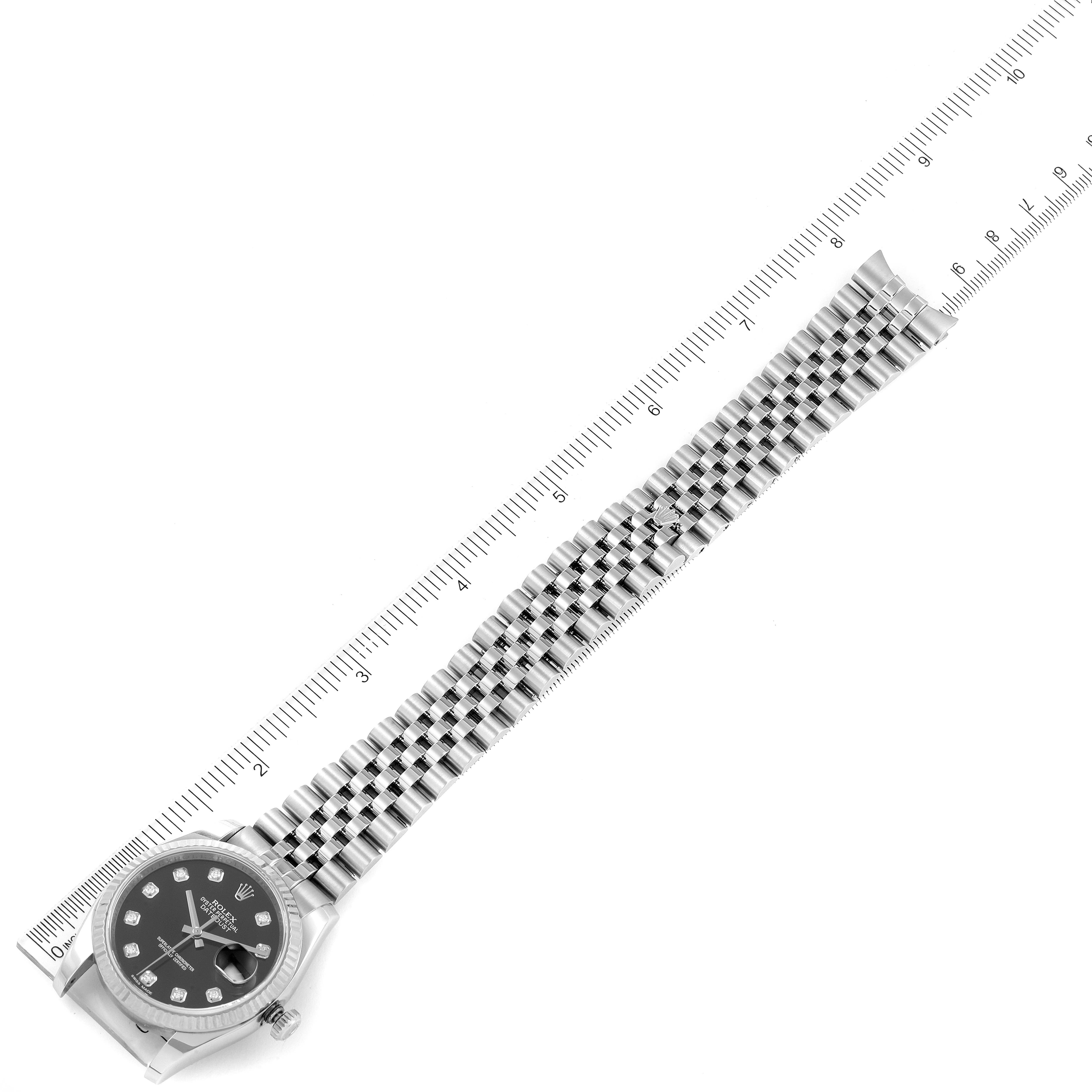 The image shows a Rolex Datejust 116234 Men
s Stainless Steel Black Dial 116234 Men
s Stainless Steel Black Dial watch laid flat with its bracelet fully extended and aligned with a ruler for measurement.