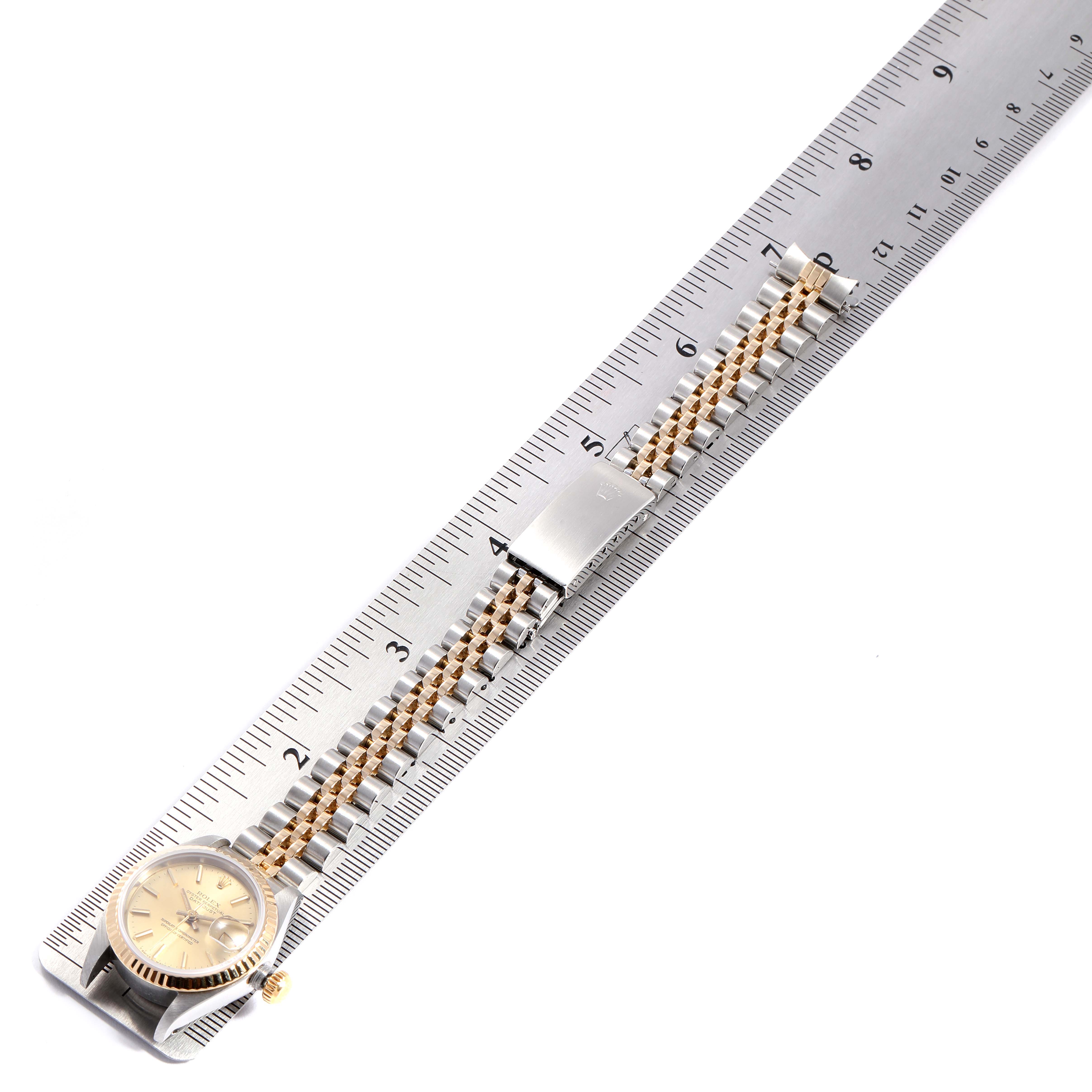 This image shows a Rolex Datejust 69173 Women's Stainless Steel Champagne Dial 69173 Women's Stainless Steel Champagne Dial watch laid flat on a ruler, displaying its face, bracelet, and clasp from an overhead angle.