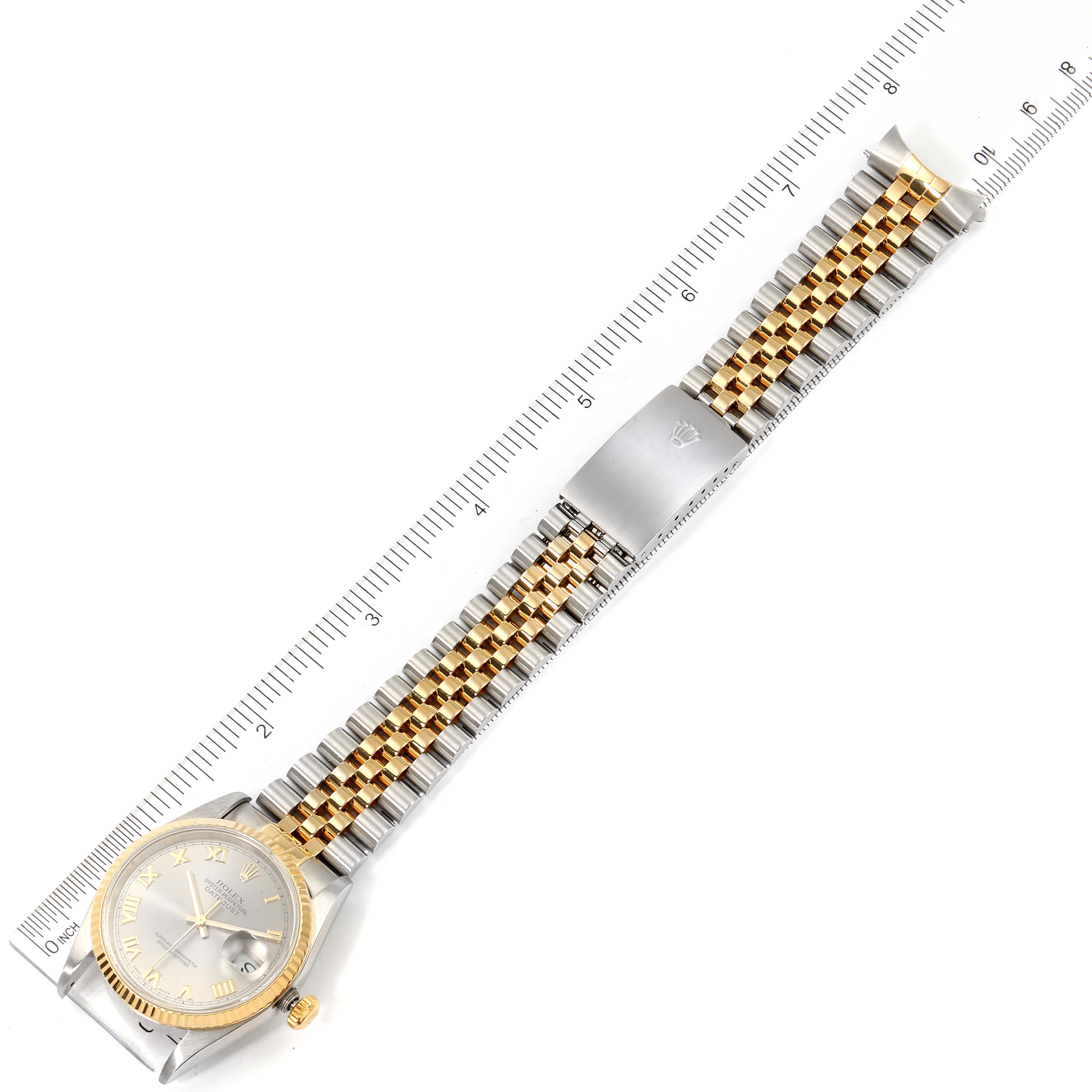 The image shows the front view of a Rolex Datejust 16233 Men's Steel and Gold (two tone) Grey Dial 16233 Men's Steel and Gold (two tone) Grey Dial watch with its full band extended alongside a ruler for scale.