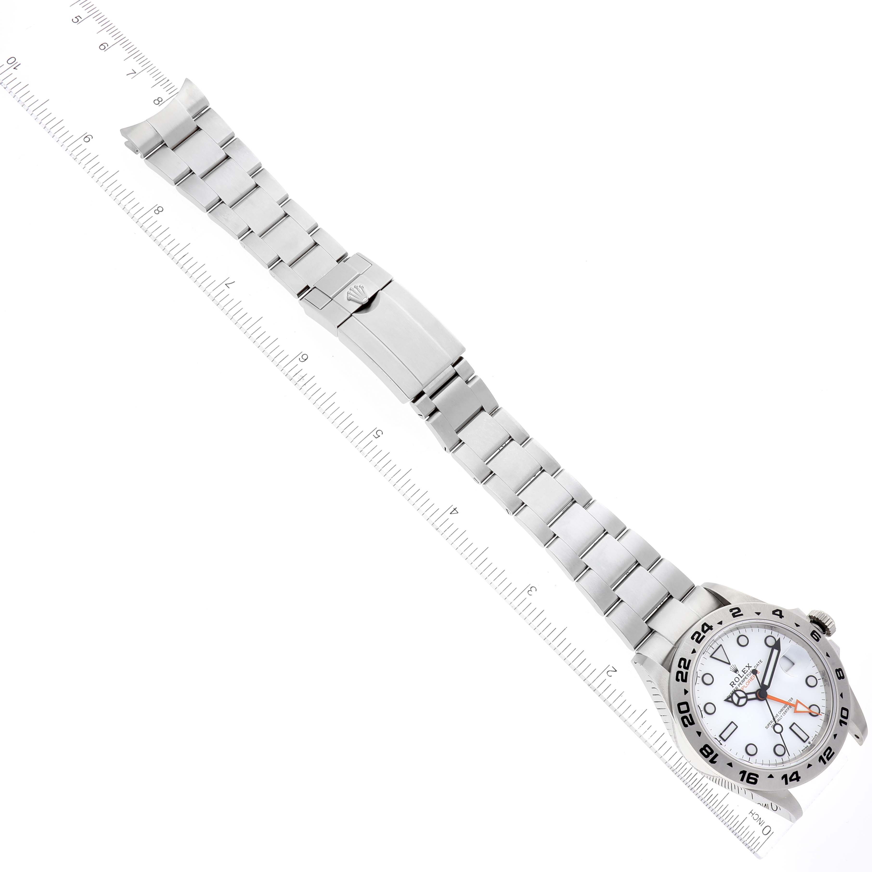 The image shows the Rolex Explorer 226570 Men
s Stainless Steel White Dial 226570 Men
s Stainless Steel White Dial watch laid flat, displaying its entire bracelet and face, with a ruler adjacent for scale.