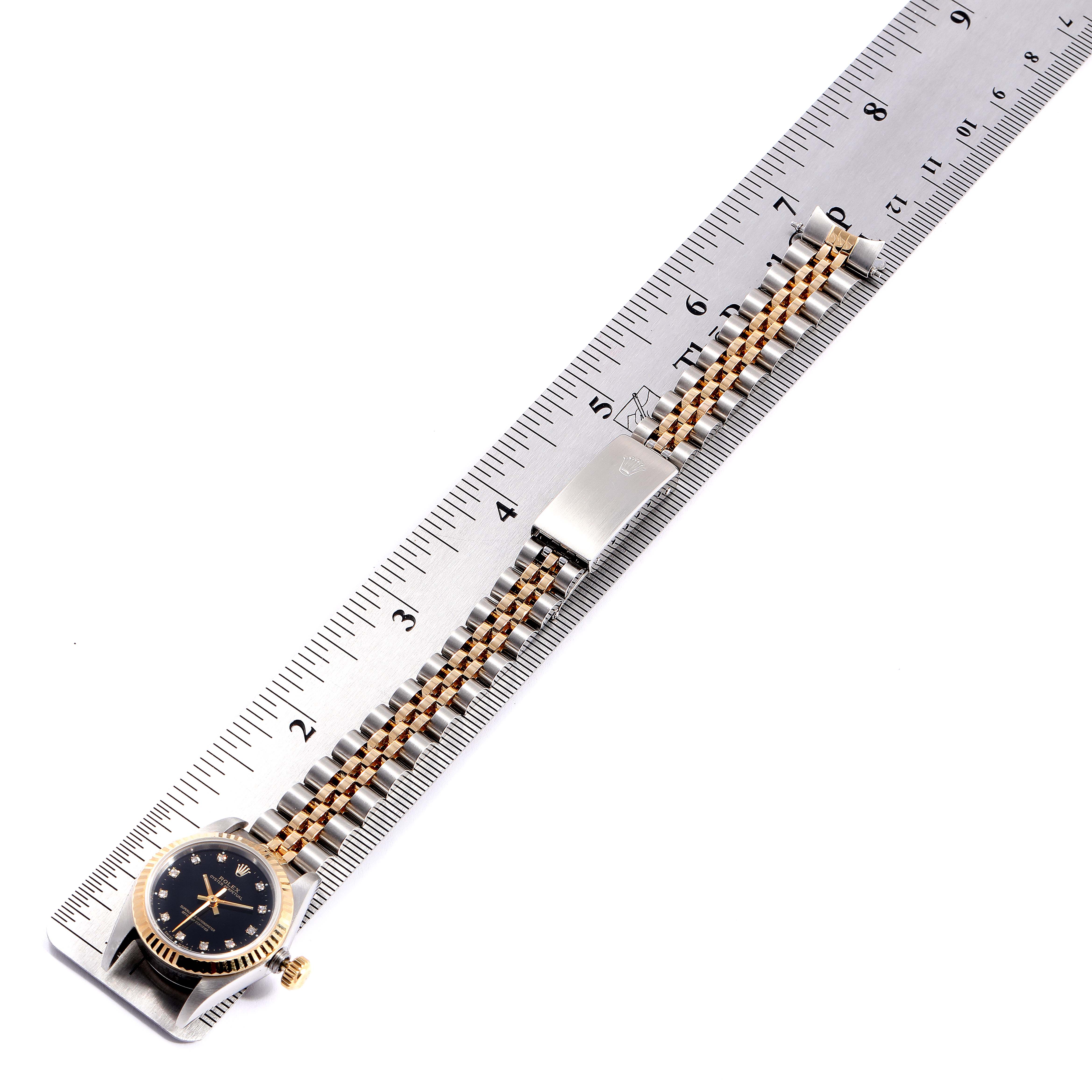 The Rolex Oyster Perpetual 67193 Women's Stainless Steel Black Dial 67193 Women's Stainless Steel Black Dial watch is shown with its strap and clasp, aligned with a ruler for measurement.