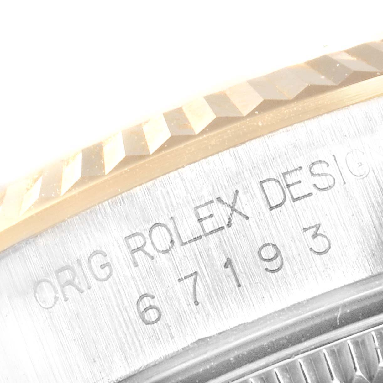 This image shows a close-up of the side of a Rolex Oyster Perpetual 67193 Women's Stainless Steel Black Dial 67193 Women's Stainless Steel Black Dial watch, displaying part of the bezel and engraved design details.