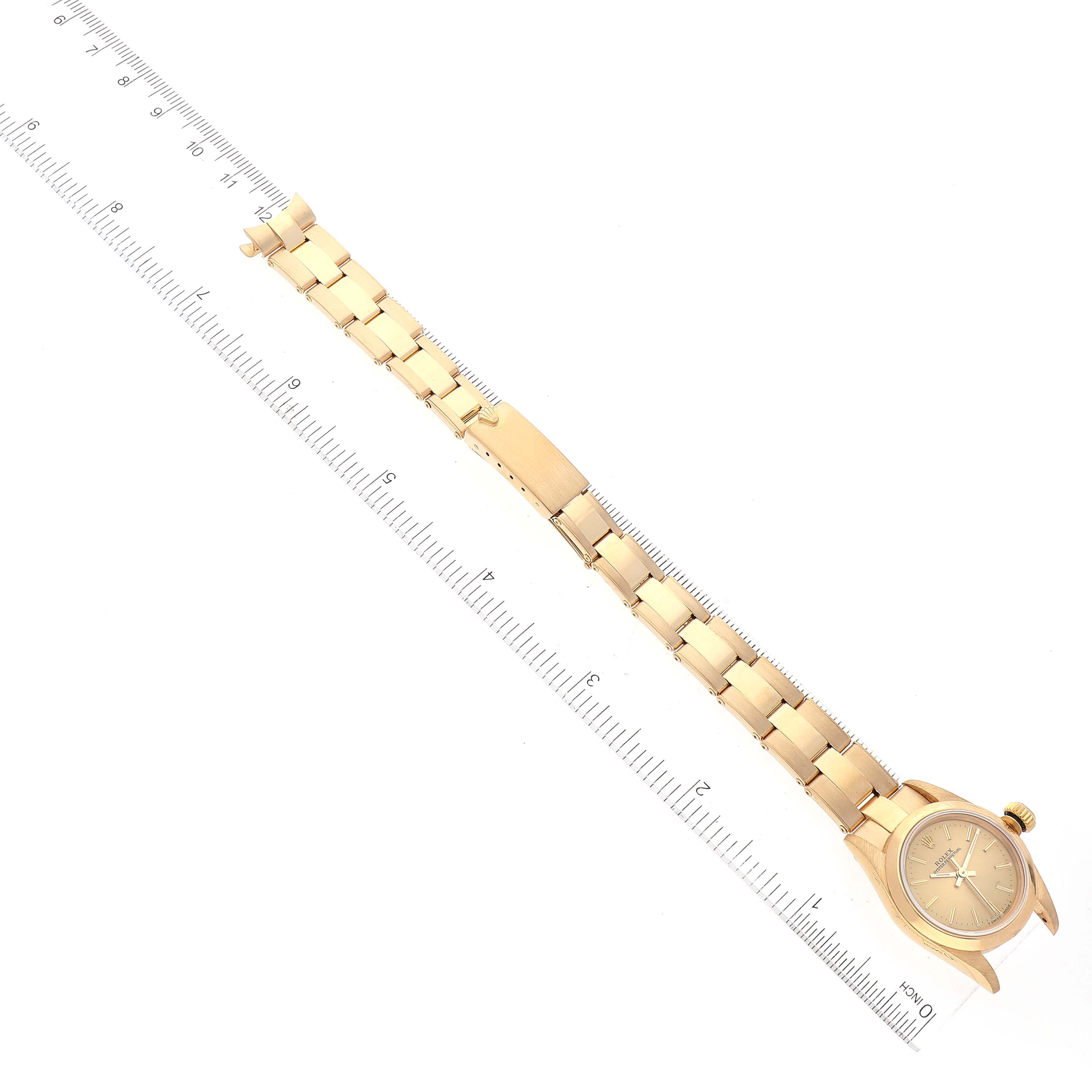 The image shows a Rolex President 67188 Women
s Yellow Gold Champagne Dial 67188 Women
s Yellow Gold Champagne Dial model watch placed flat with the wristband extended, positioned alongside a ruler for scale.