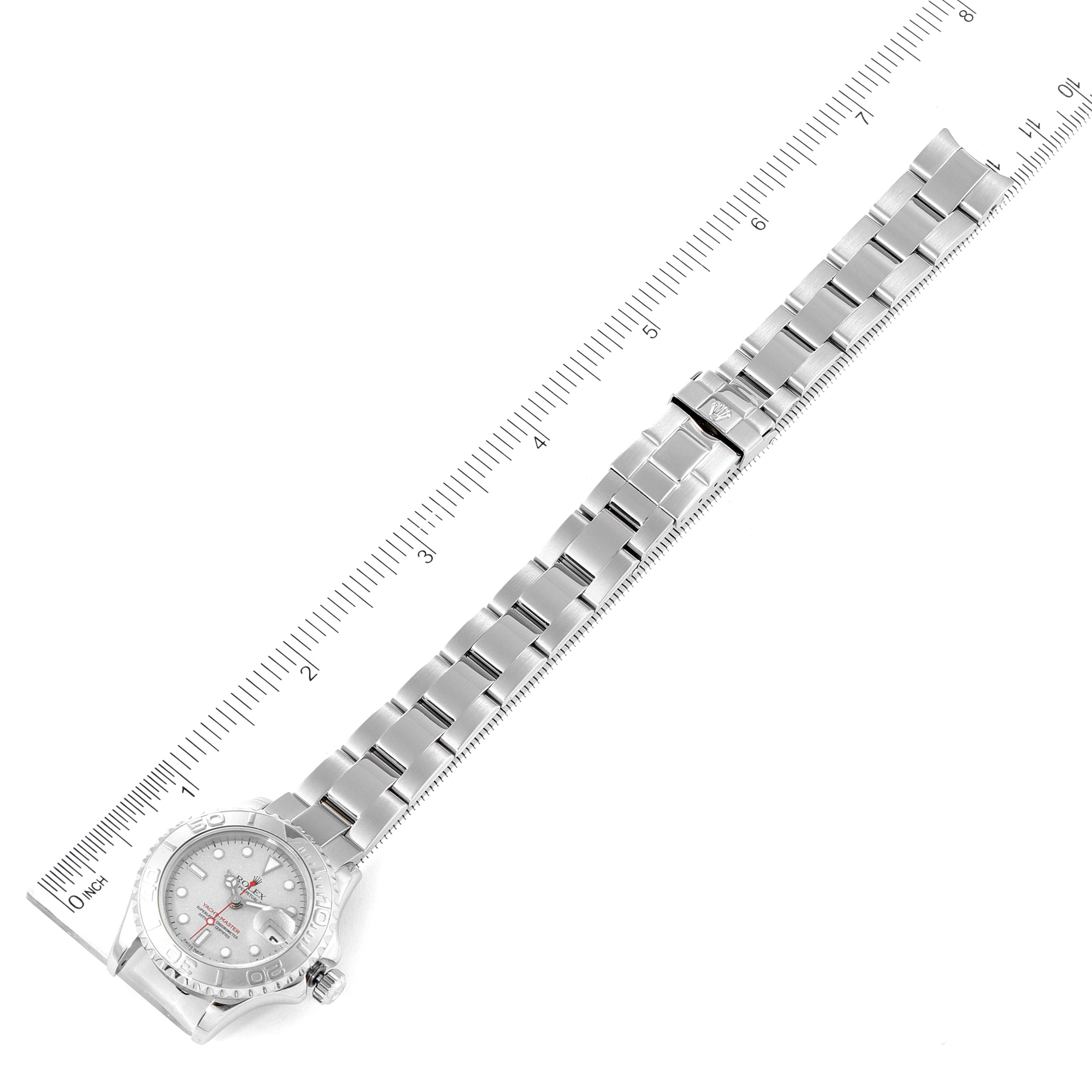 The image shows a top-down view of the Rolex Yacht-Master 169622 Women's Stainless Steel Silver Dial 169622 Women's Stainless Steel Silver Dial watch with its full metal bracelet extended and rulers for scale on either side.