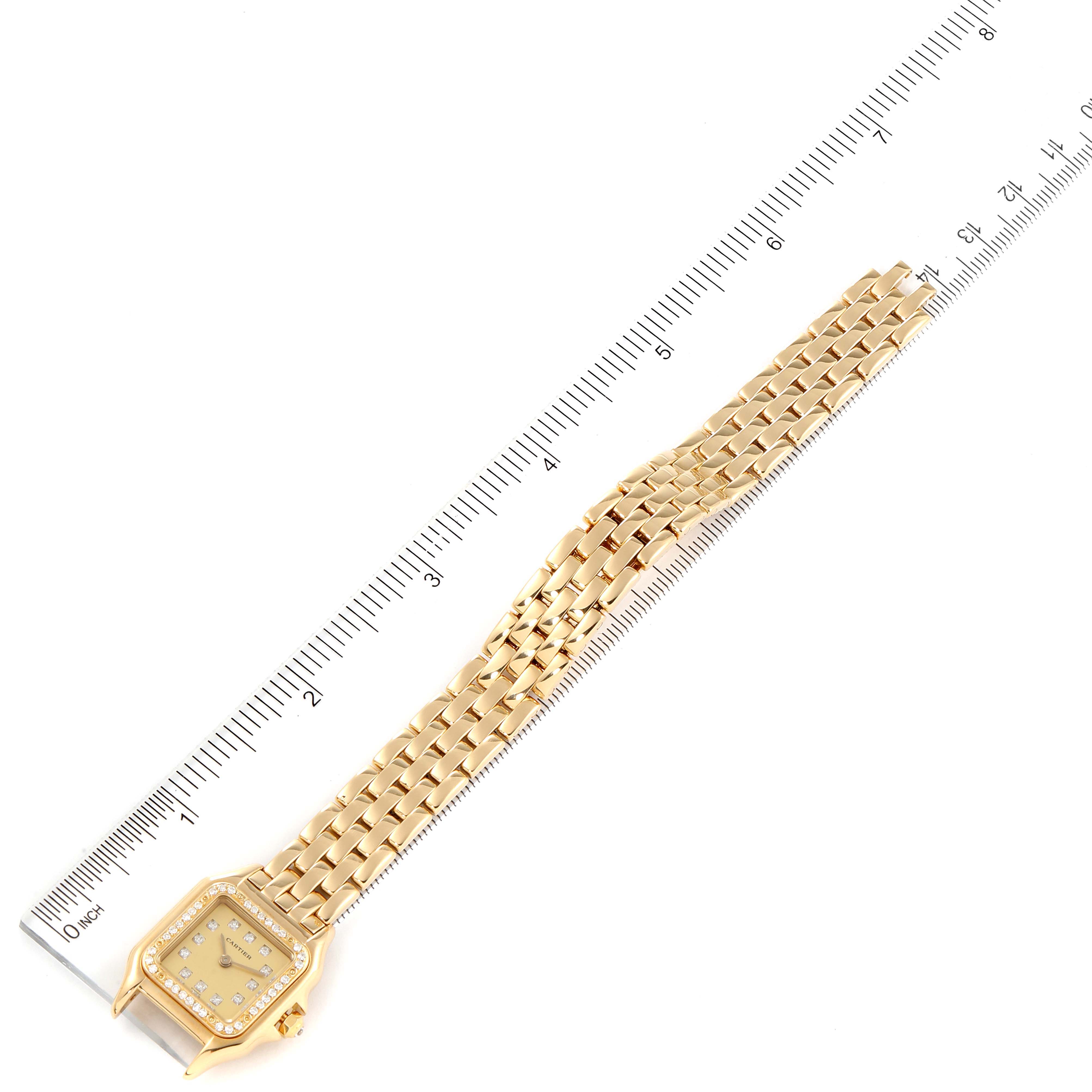 The Cartier Panthere 866911 Women's Yellow Gold Champagne Dial 866911 Women's Yellow Gold Champagne Dial watch is shown at a top-down angle, featuring its face and entire gold bracelet laid next to a ruler.