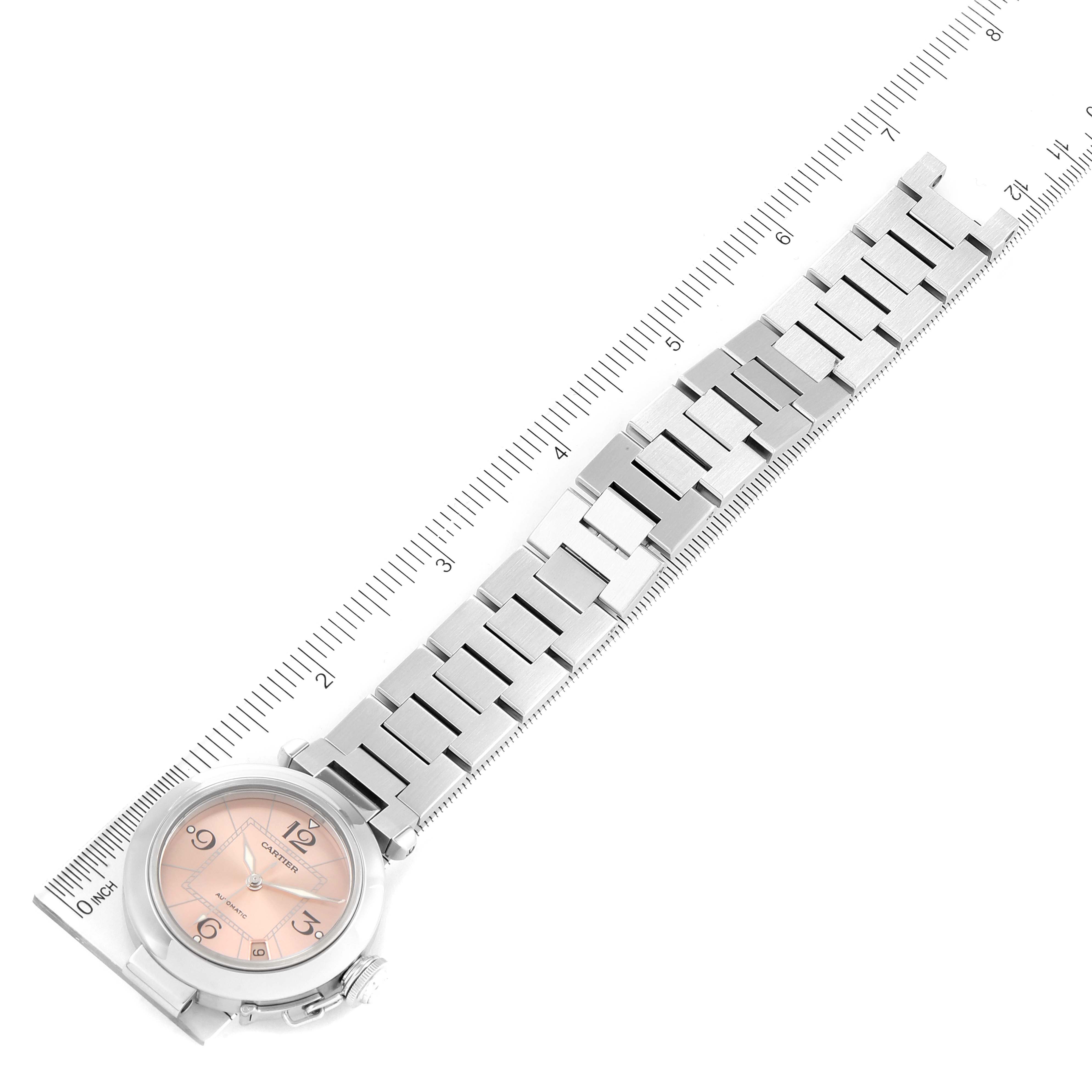 The image shows a top-down view of a Cartier Pasha W31075M7 Women's Stainless Steel Pink Dial W31075M7 Women's Stainless Steel Pink Dial watch, displaying its face, bracelet, and a ruler for scale.