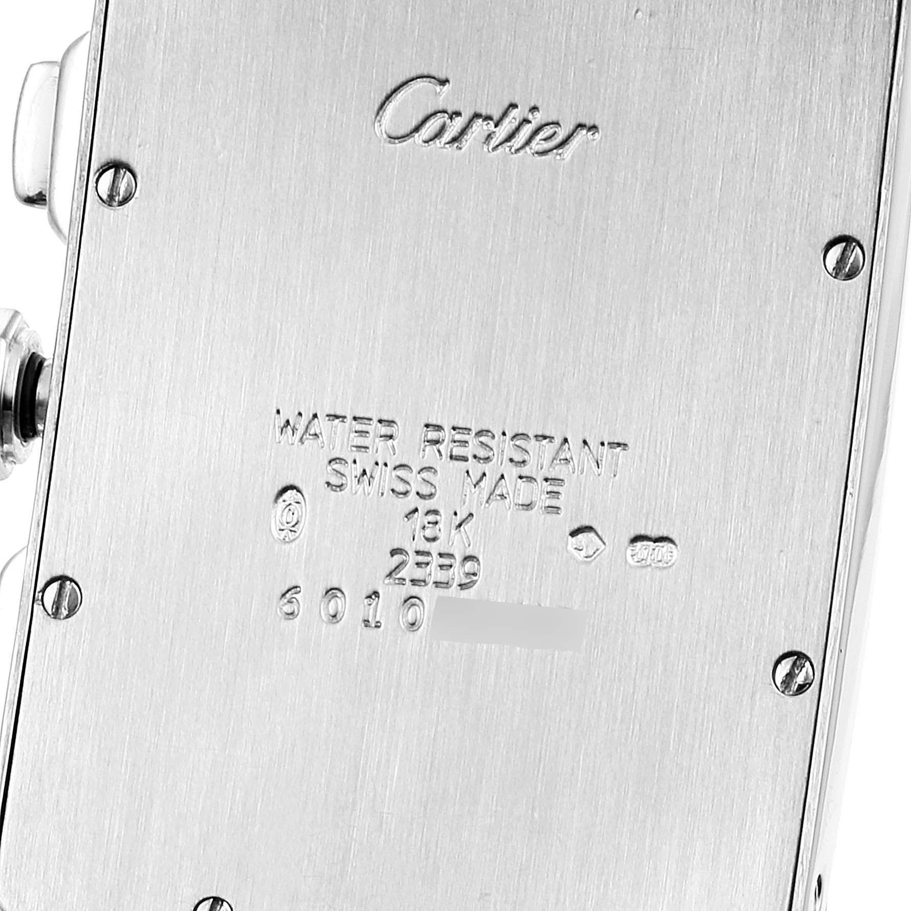 The image shows the back case of the Cartier Tank Américaine watch, displaying engraved details and screws.