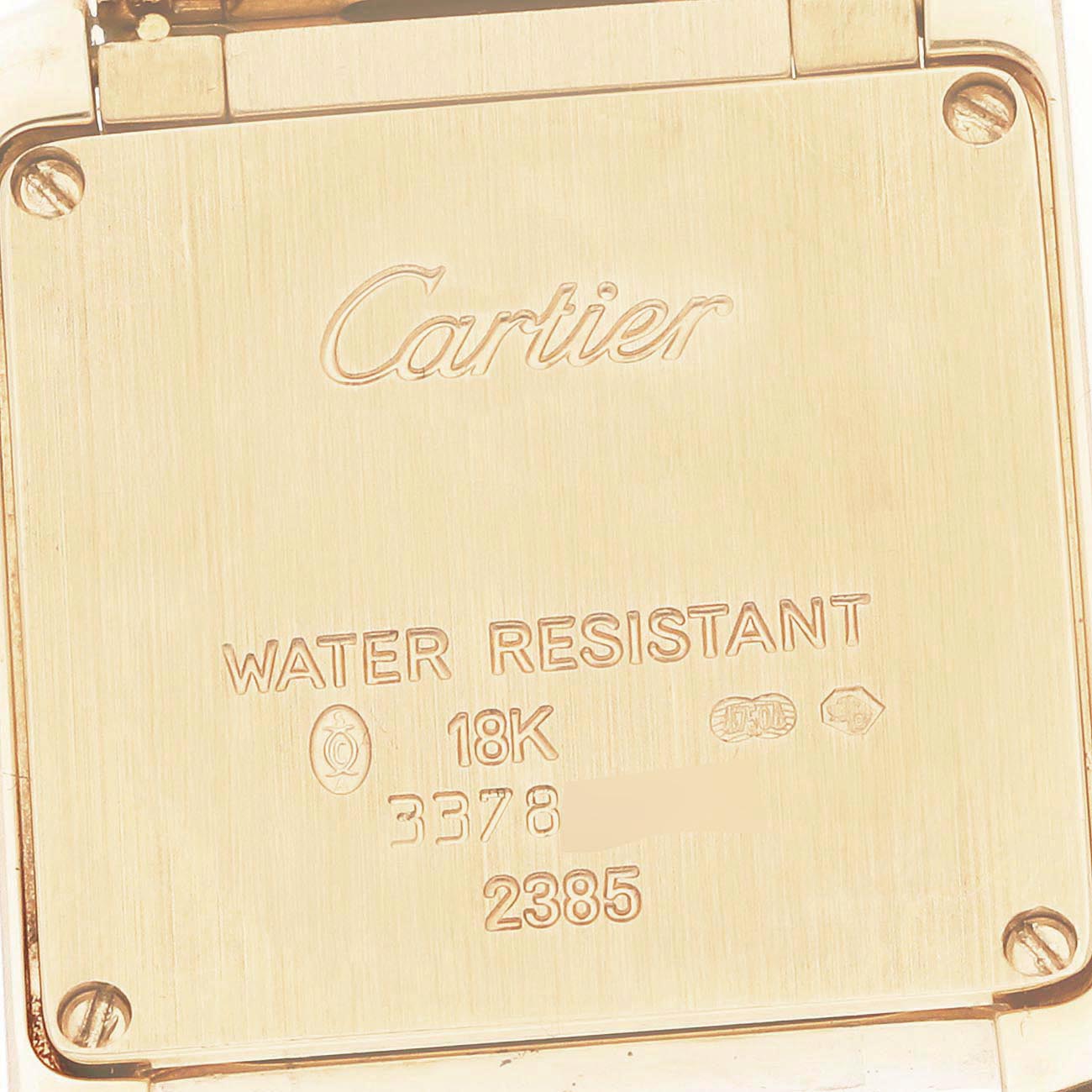 The image shows the back plate of a Cartier Tank Française watch, featuring engravings and hallmarks.