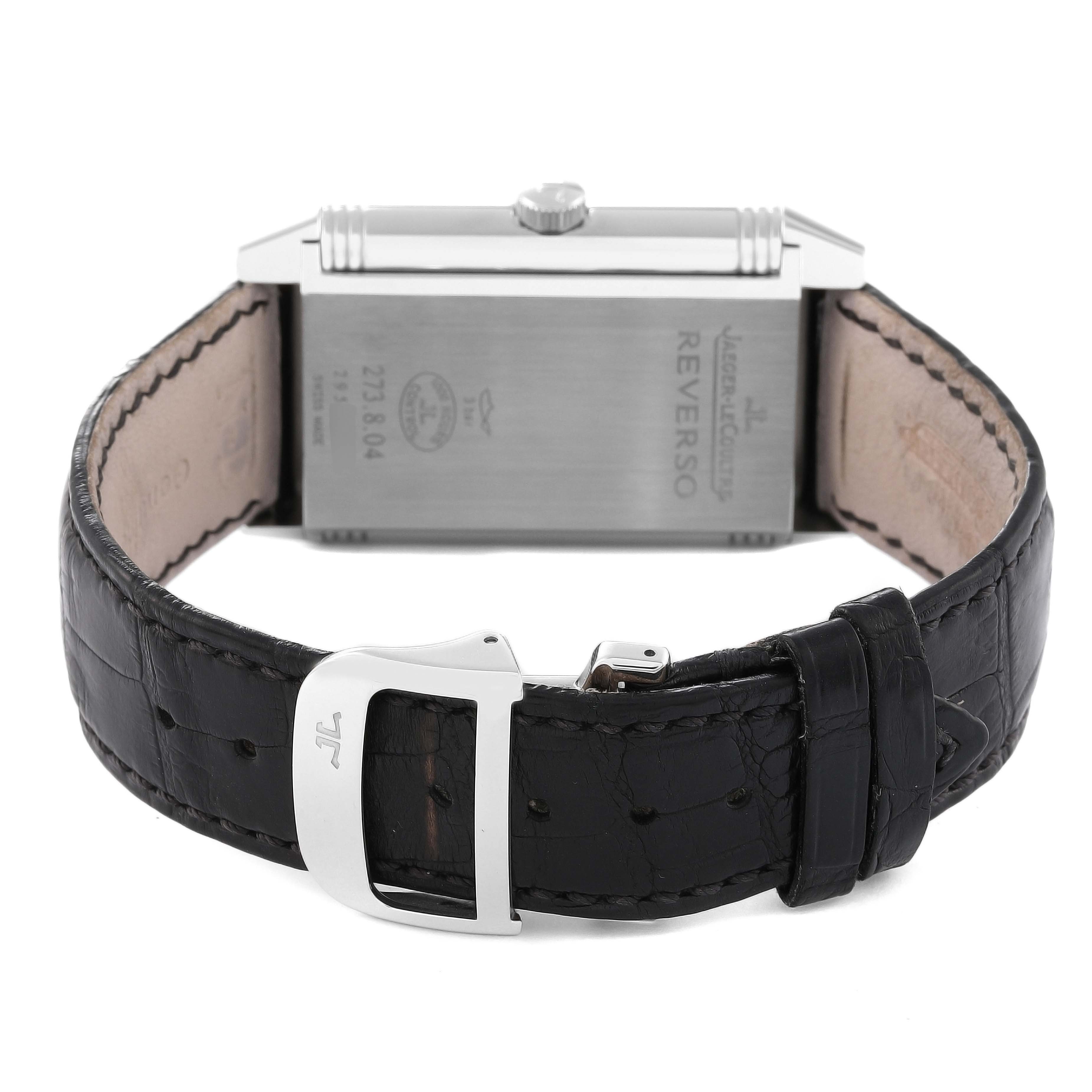 The image shows the back and clasp of a Jaeger-LeCoultre Reverso watch, featuring a black leather strap and stainless steel case.