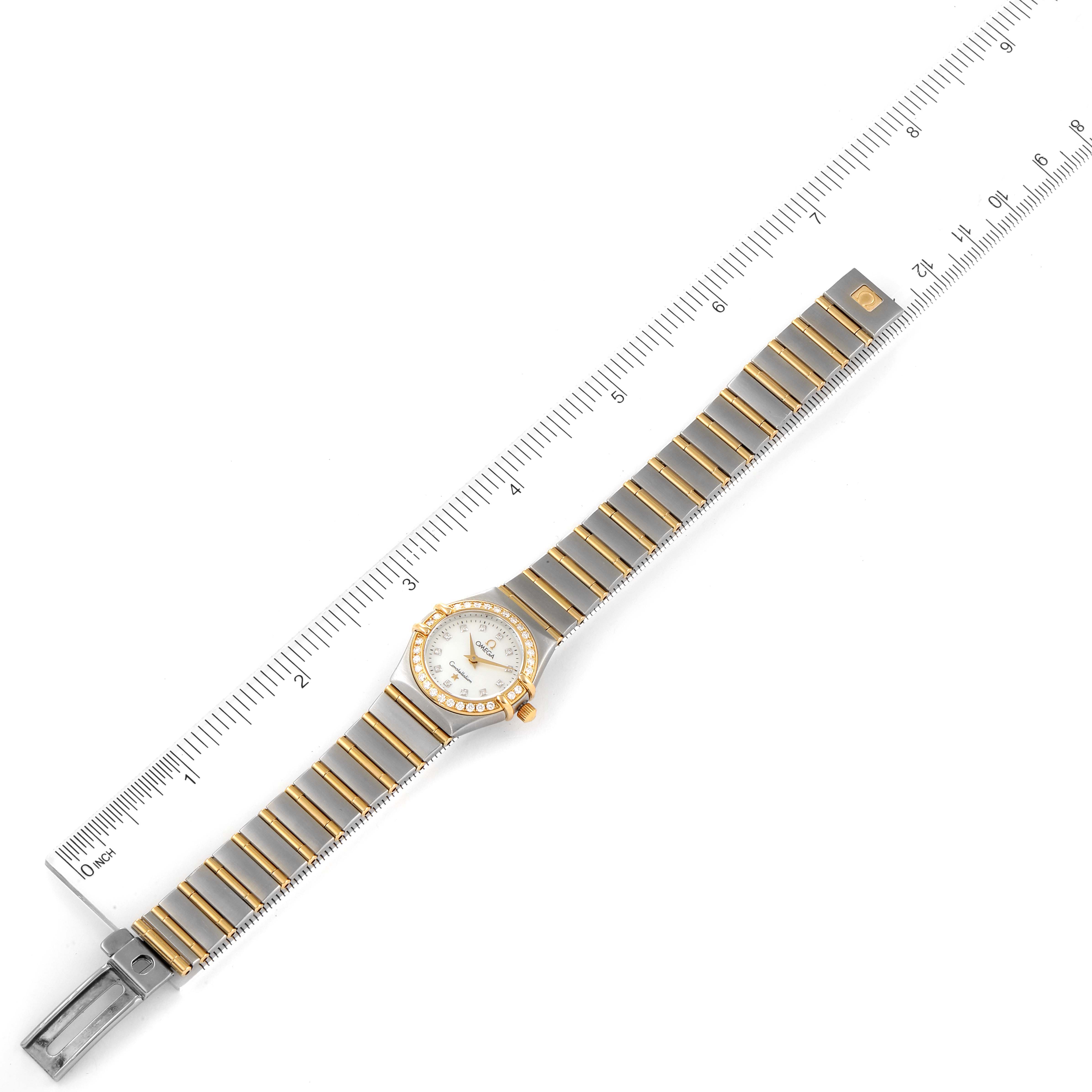 The image shows an Omega 1267.75.00 Women's Steel and Gold (two tone) Mother of Pearl Dial 1267.75.00 Women's Steel and Gold (two tone) Mother of Pearl Dial Constellation 95 Mother of Pearl Diamond Ladies Watch 1267.75.00 laid parallel to a ruler, displaying the band and face.