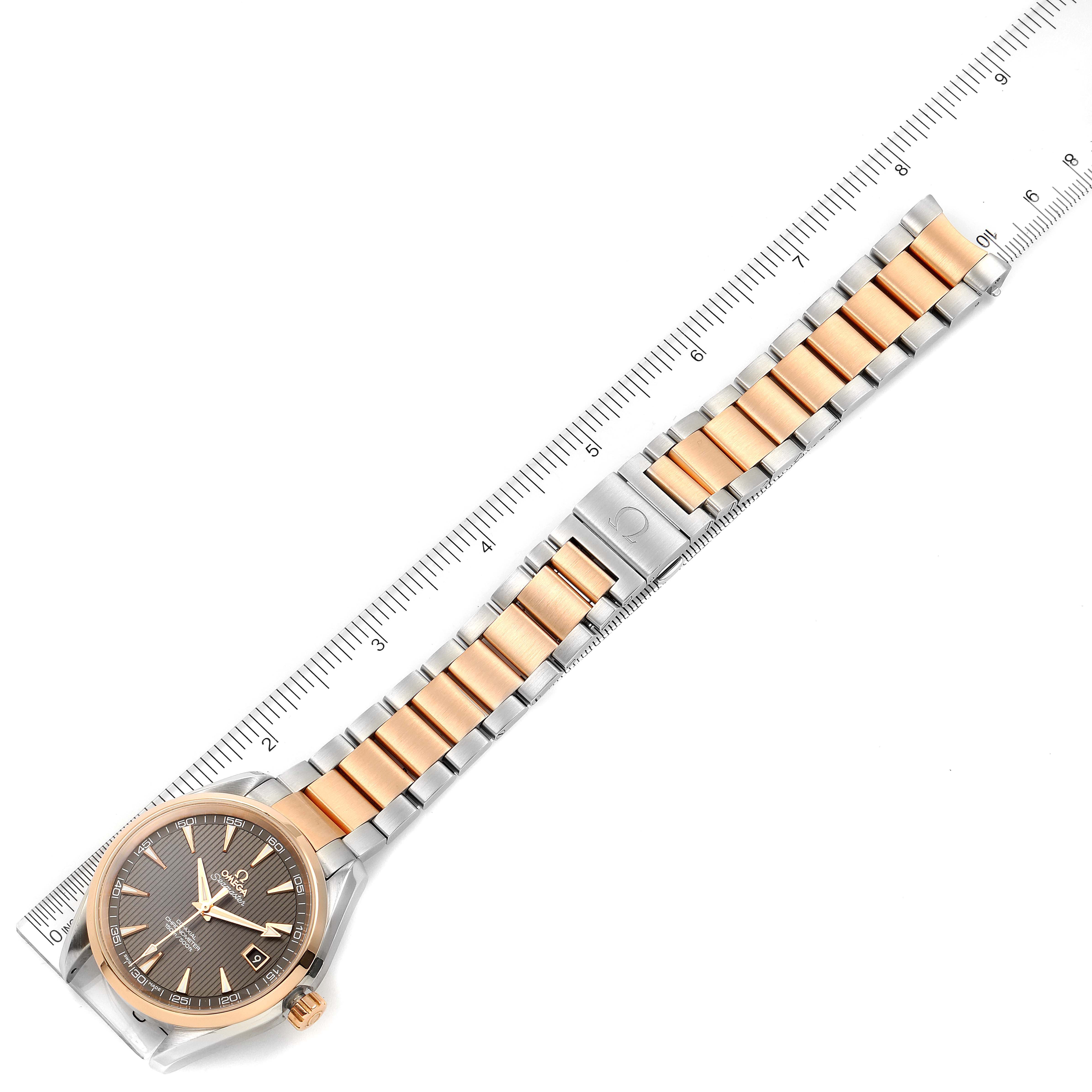 This image shows the full Omega Aqua Terra 231.20.42.21.06.001 Men's Steel and Gold (two tone) Grey Dial 231.20.42.21.06.001 Men's Steel and Gold (two tone) Grey Dial watch laid flat next to a ruler, displaying the face, band, and clasp.