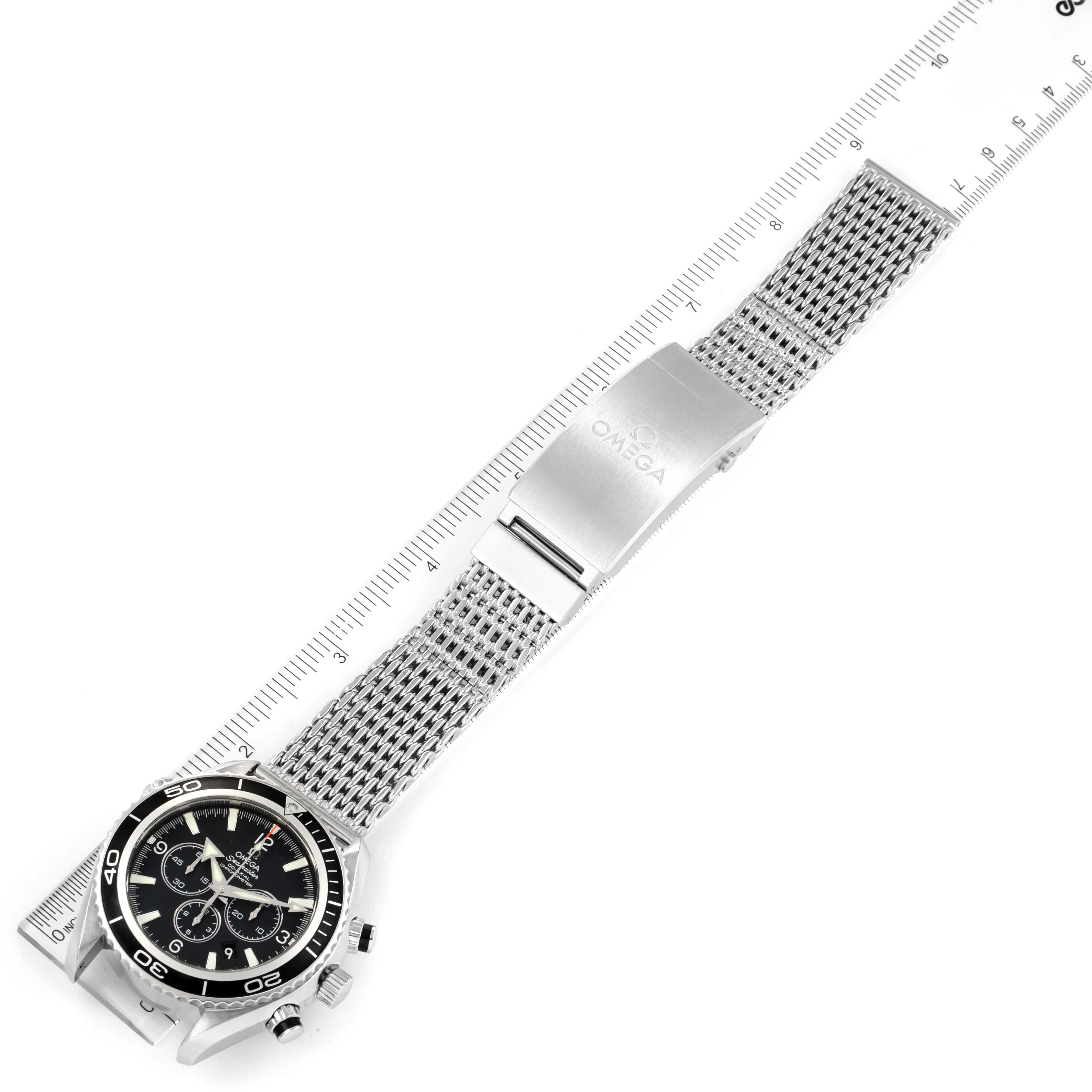 The image shows an overhead view of the Omega Planet Ocean 2210.50.00 Men's Stainless Steel Black Dial 2210.50.00 Men's Stainless Steel Black Dial watch, highlighting the face, bezel, and metal mesh bracelet with clasp.