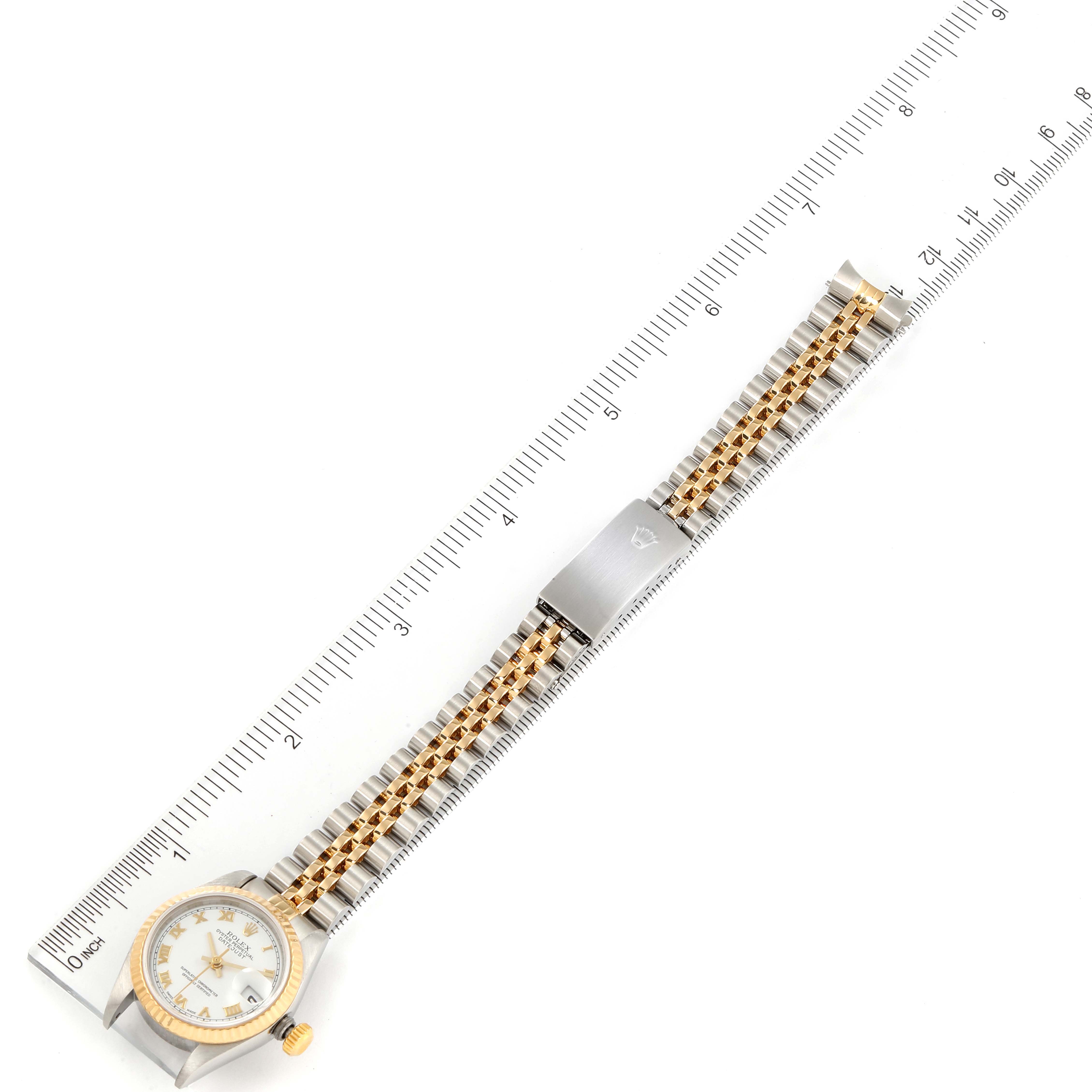 The image shows a top-down view of a Rolex Datejust 79173 Women's Steel and Gold (two tone) White Dial 79173 Women's Steel and Gold (two tone) White Dial watch, highlighting its bracelet and clasp alongside a measurement scale.