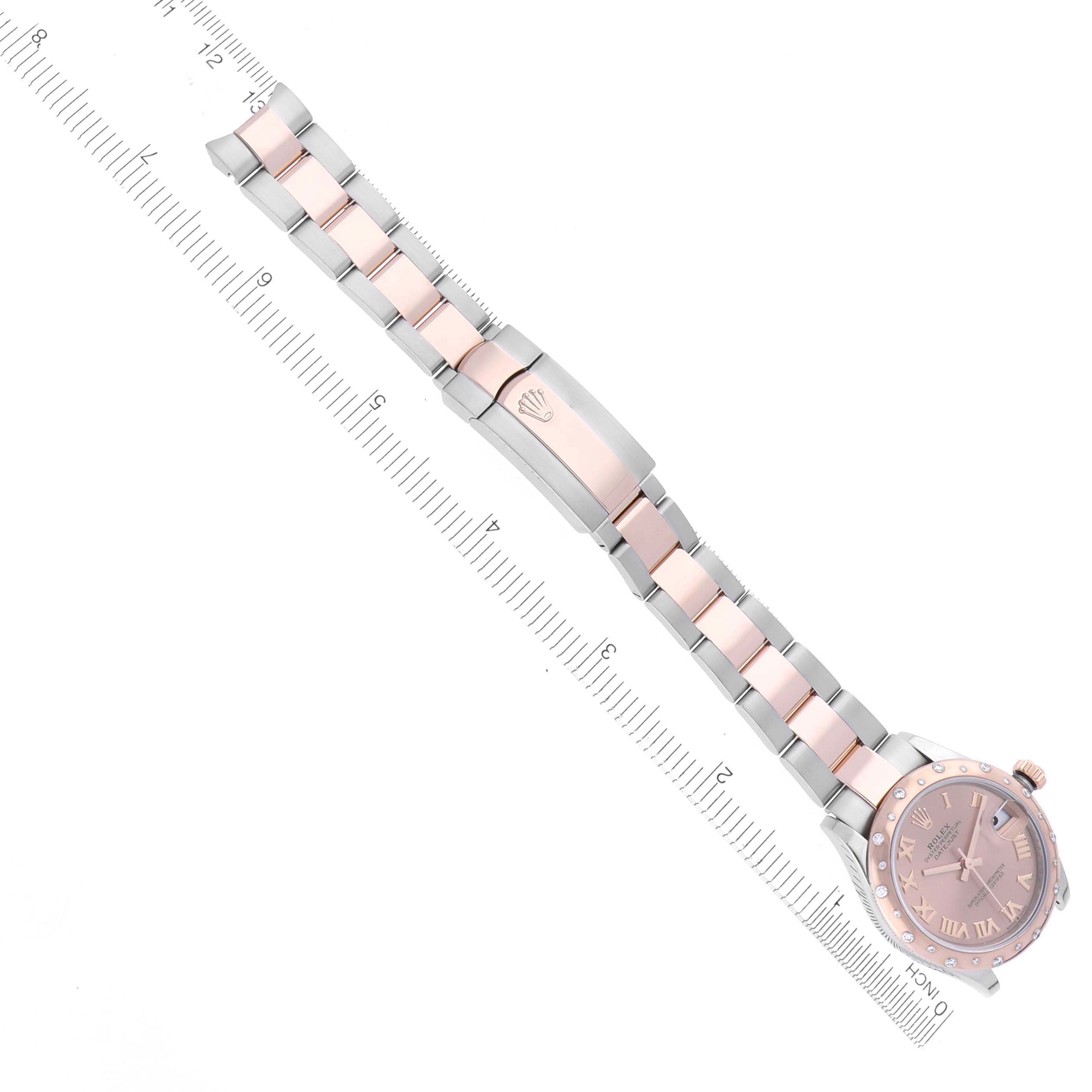 The image shows a top view of a Rolex Mid-Size 278241 Women's Steel and Gold (two tone) Pink Dial 278241 Women's Steel and Gold (two tone) Pink Dial watch with its bracelet and clasp, positioned alongside a ruler for scale.
