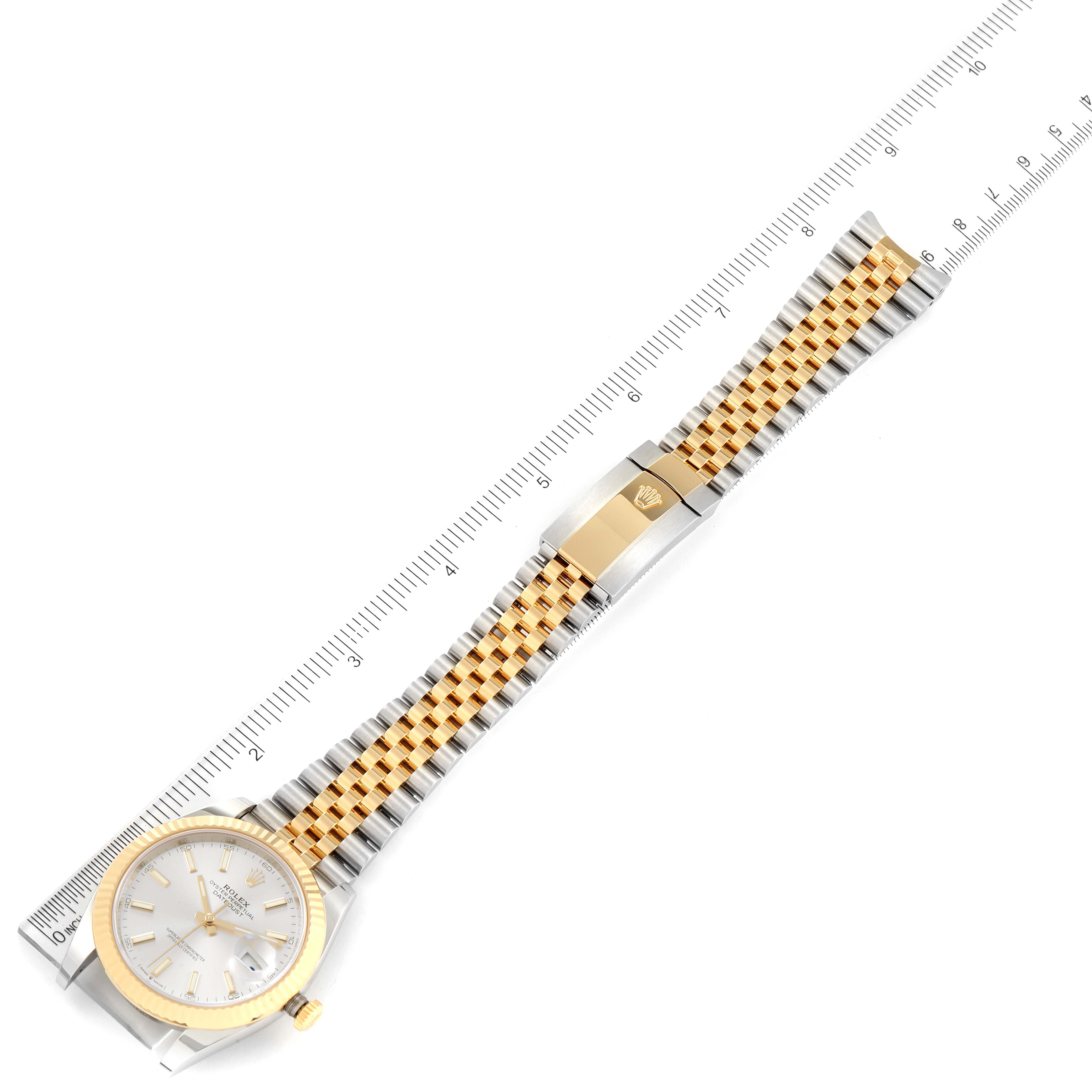 The image shows a top-down view of a Rolex Datejust 41 126333 Men's Steel and Gold (two tone) Silver Dial 126333 Men's Steel and Gold (two tone) Silver Dial watch with a gold and silver jubilee bracelet next to a ruler.