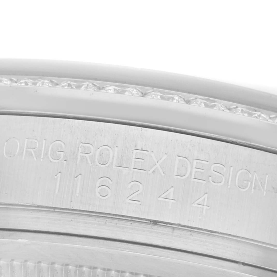 The image shows a close-up of the side of a Rolex Datejust 116244 Men
s Stainless Steel Black Dial 116244 Men
s Stainless Steel Black Dial watch with "ORIG. ROLEX DESIGN 116244" engraved on it.