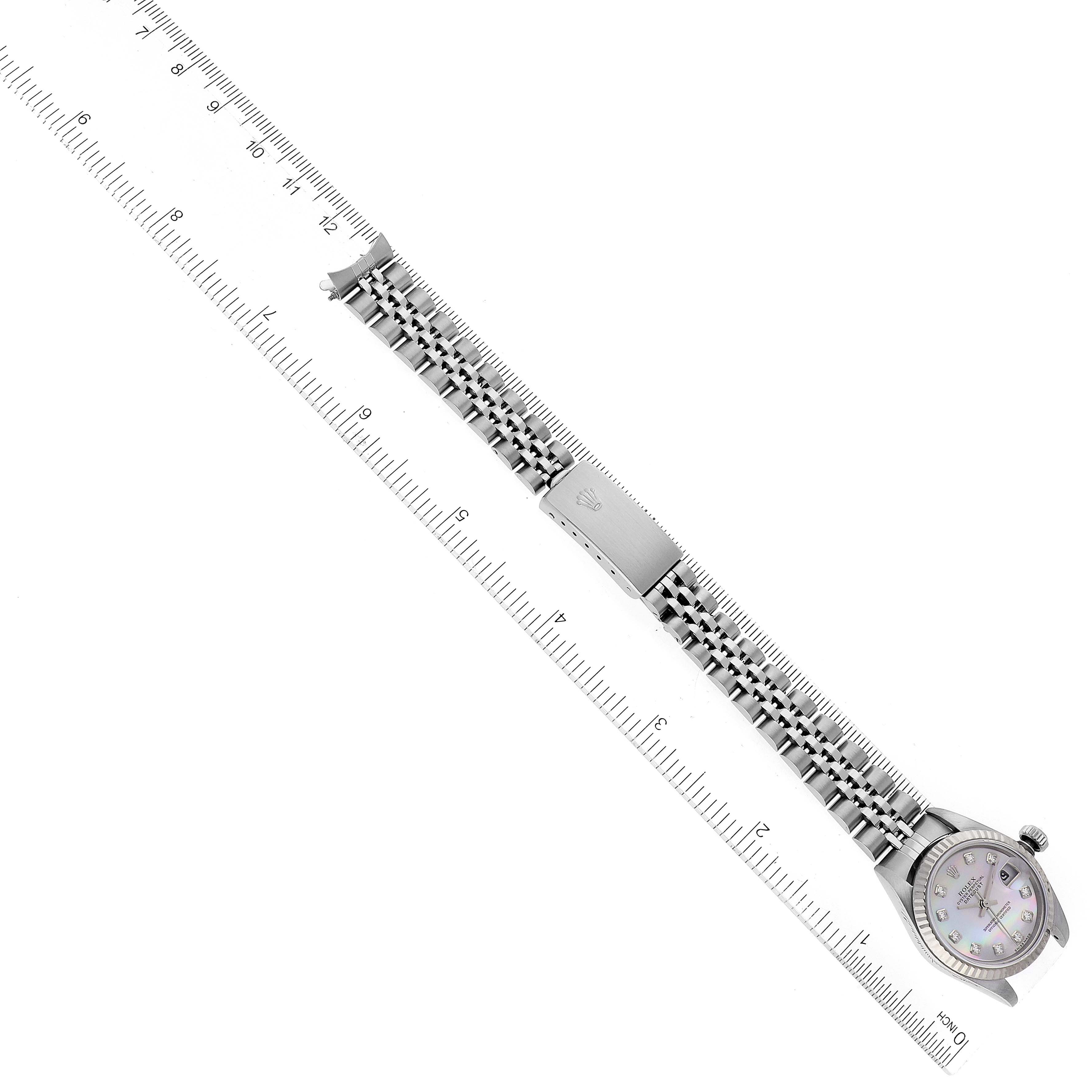 This image shows a Rolex Datejust 79174 Women's Stainless Steel Mother of Pearl Dial 79174 Women's Stainless Steel Mother of Pearl Dial watch placed next to a ruler, displaying the entire strap and face at a diagonal angle.