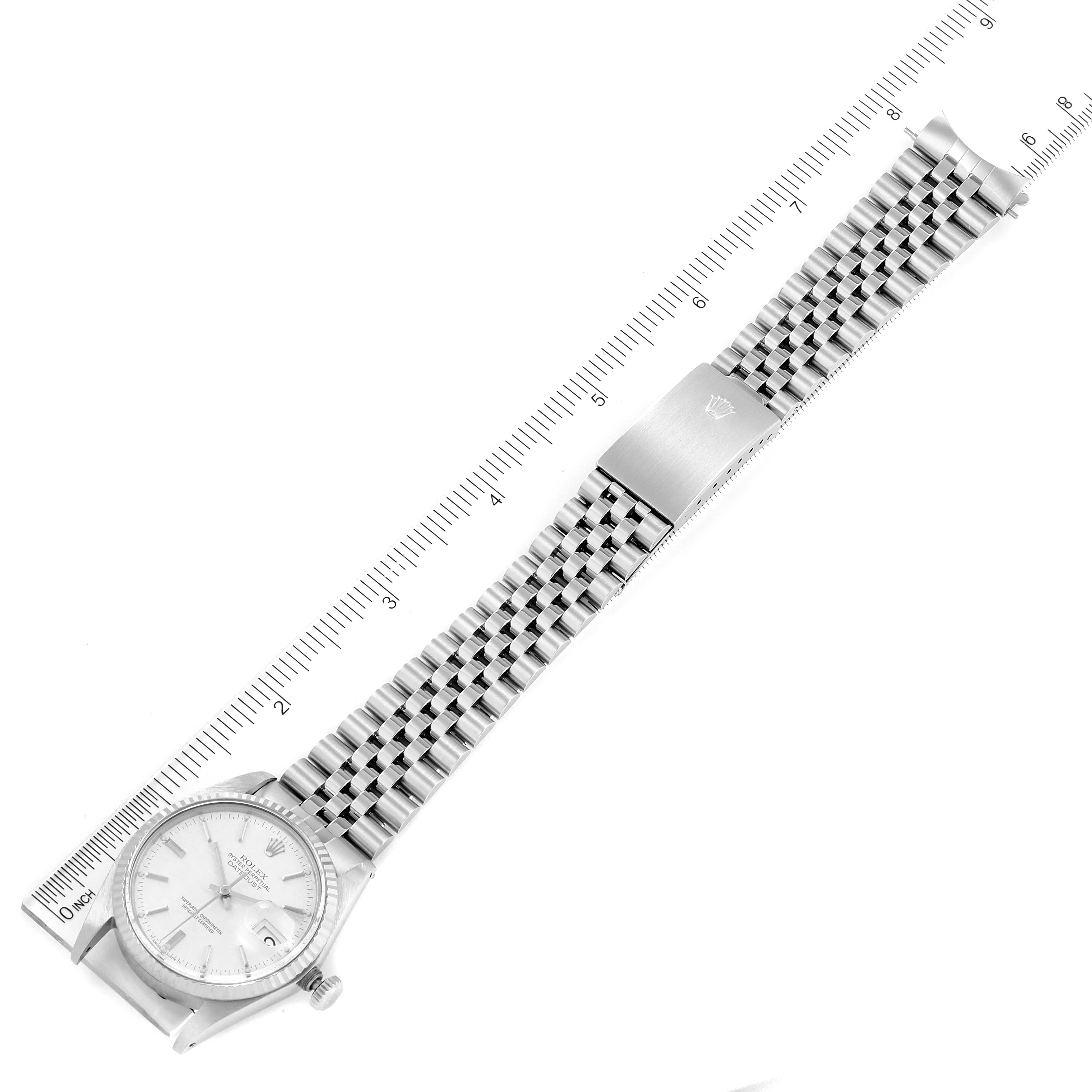 The image shows a top-down view of a Rolex Vintage Collection 16014 Men's Stainless Steel Silver Dial 16014 Men's Stainless Steel Silver Dial watch, including the face, crown, and metal bracelet, with a measurement scale beside it.