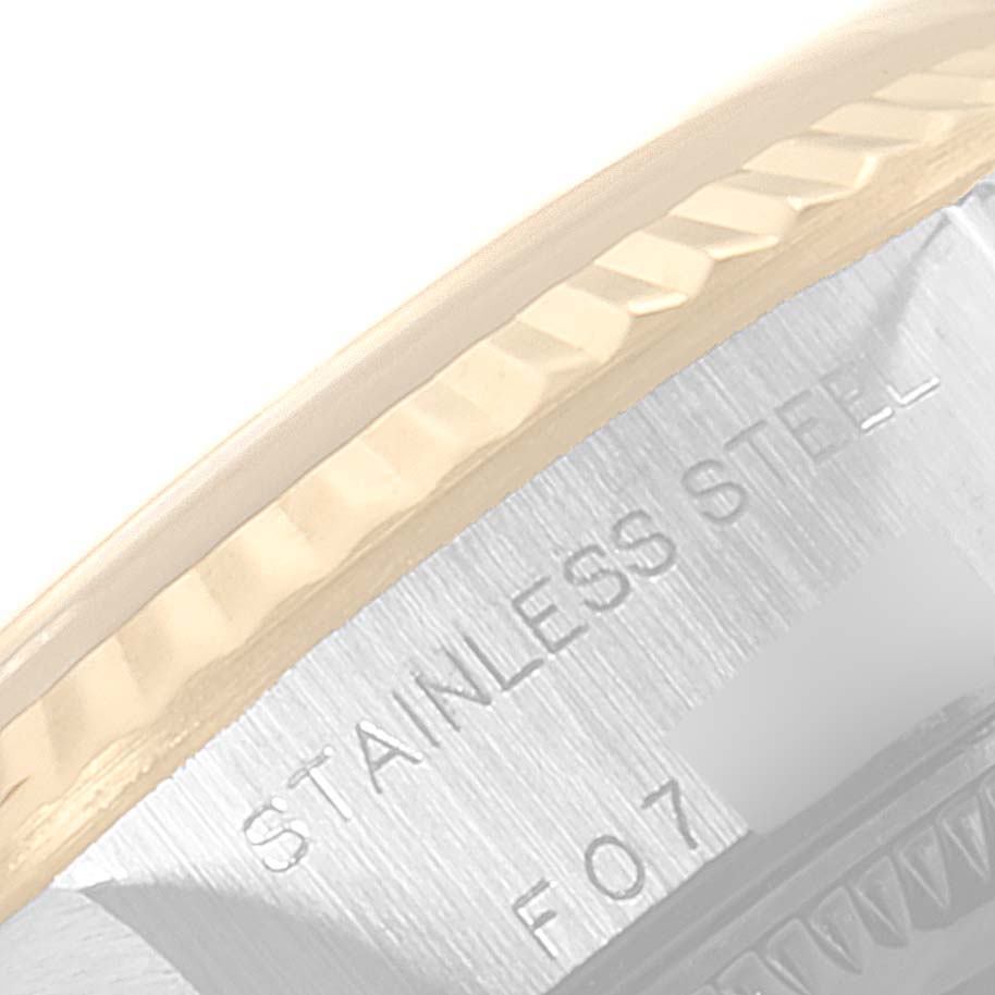 This close-up image shows the fluted bezel and case edge of the Rolex Datejust 79173 Women's Steel and Gold (two tone) Champagne Dial 79173 Women's Steel and Gold (two tone) Champagne Dial watch with engravings on the inner case.