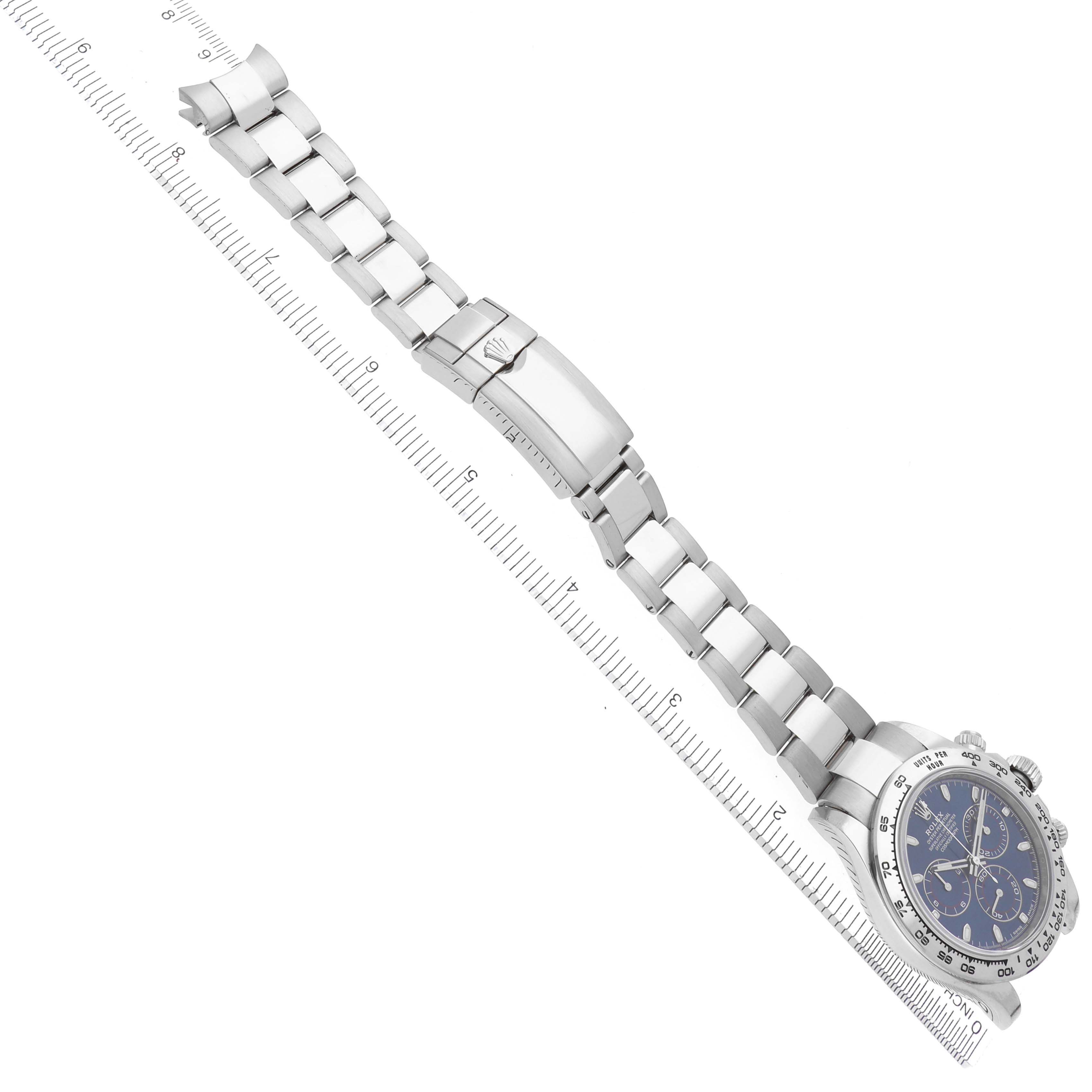 The Rolex Daytona 116509 Men's White Gold Blue Dial 116509 Men's White Gold Blue Dial watch is shown from an overhead angle, highlighting the bracelet, clasp, and watch face, aligned with a ruler.