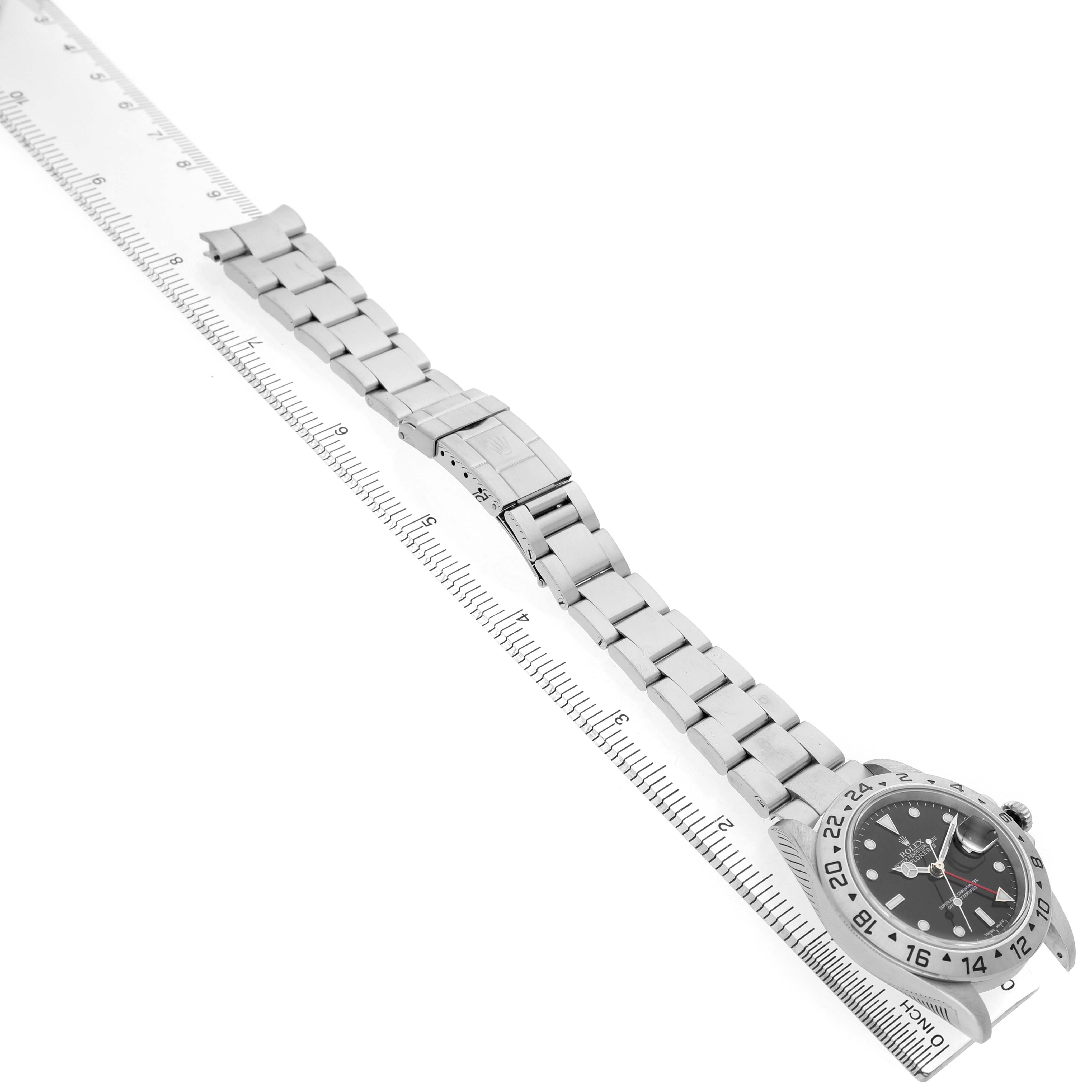 The Rolex Explorer 16570 Men's Stainless Steel Black Dial watch is shown from an angled side view, highlighting the full bracelet and clasp using a ruler for scale.