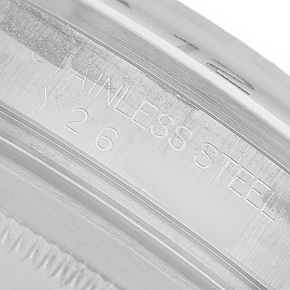 The image shows a close-up of the side of a Rolex Explorer 16570 Men's Stainless Steel White Dial watch case, highlighting "STAINLESS STEEL" engraving and serial numbers.